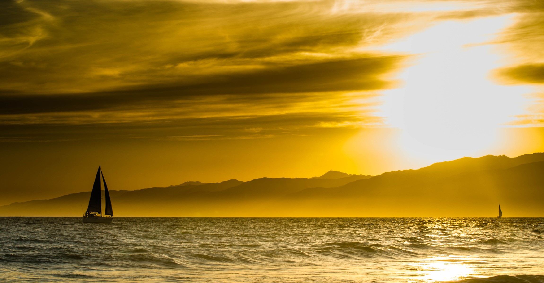 Sailboats on the ocean at sunset with mountains HD Wallpaper