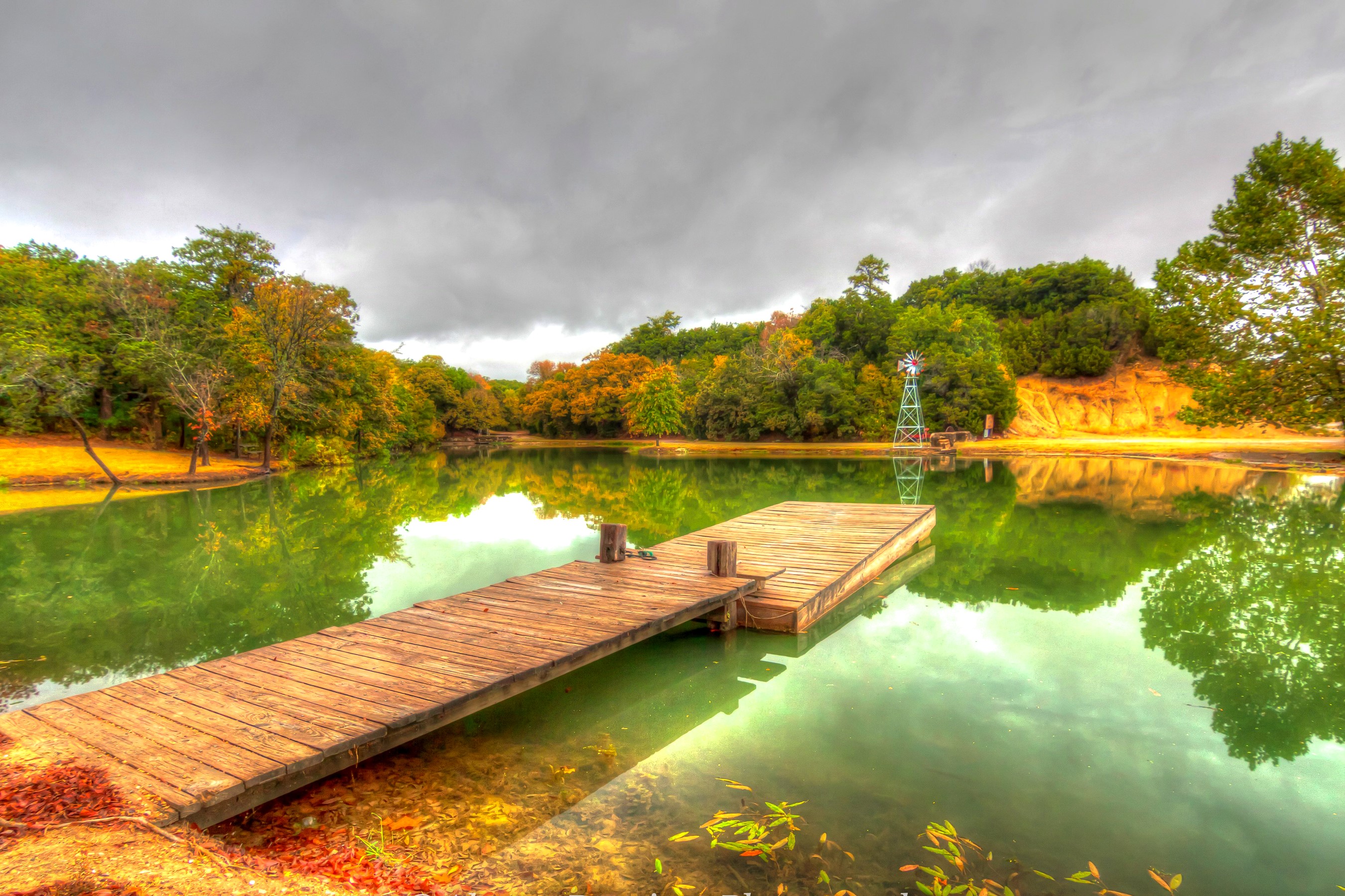 Wooden dock on a pond with trees and a windmill HD Wallpaper