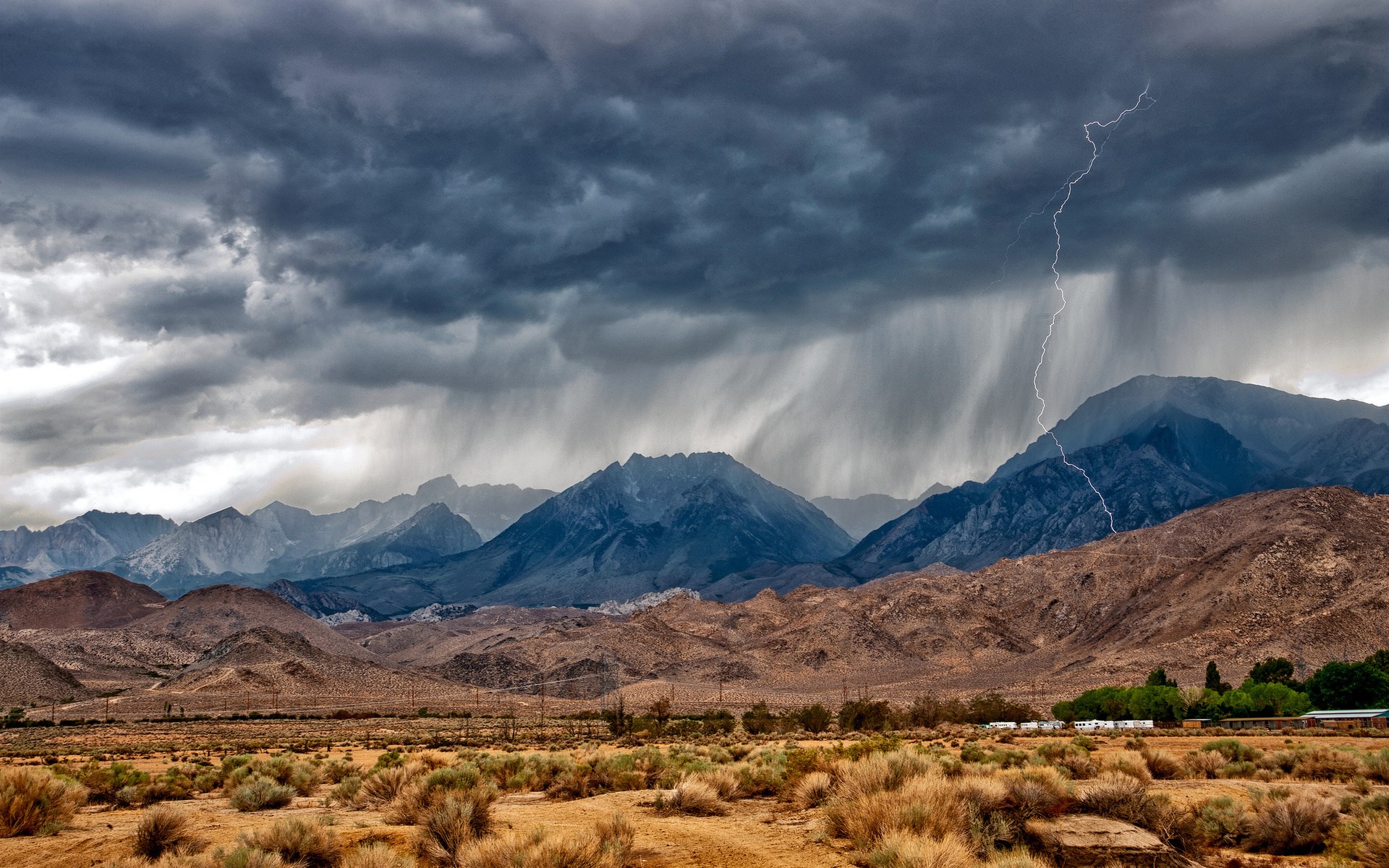 Stormy mountains with lightning and rain over desert landscape HD Wallpaper