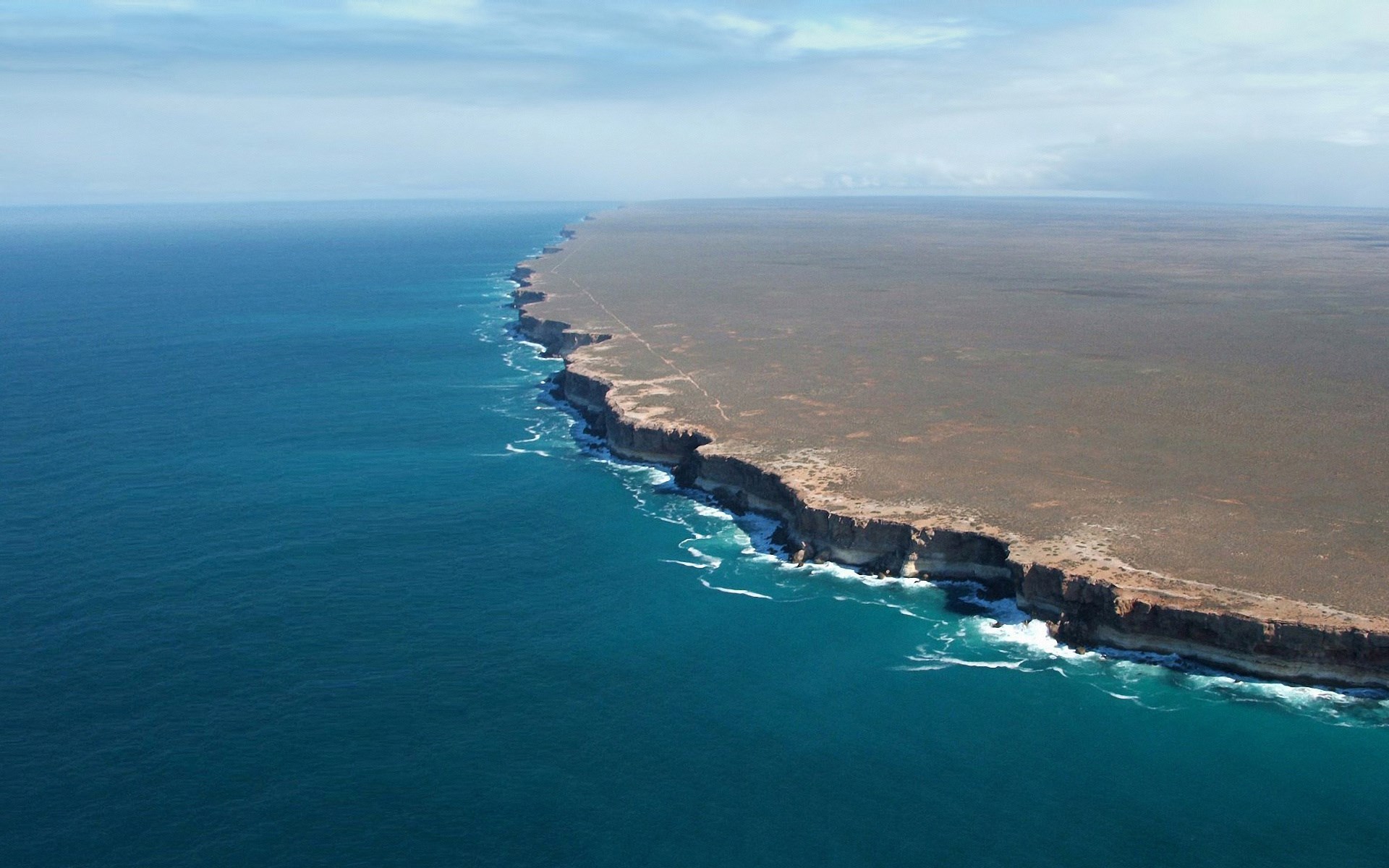 Coastal cliffs meeting the ocean HD Wallpaper