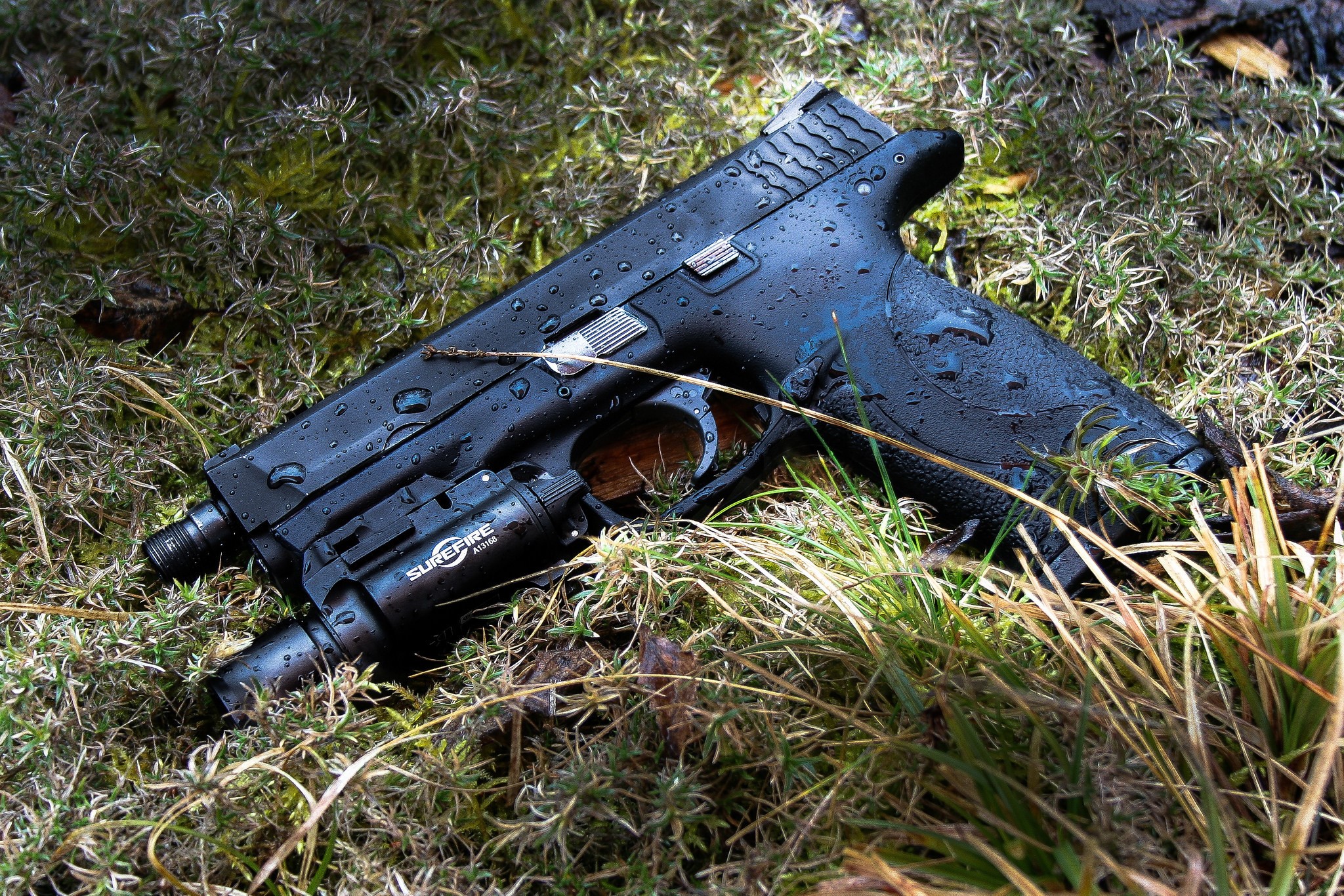 Smith & Wesson pistol with SureFire light on grass HD Wallpaper