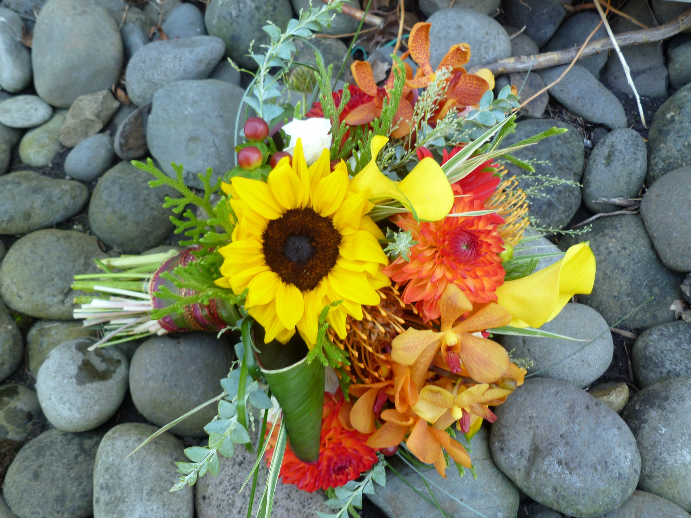 Bouquet of sunflowers, dahlias, orchids, and calla lilies on stones HD Wallpaper