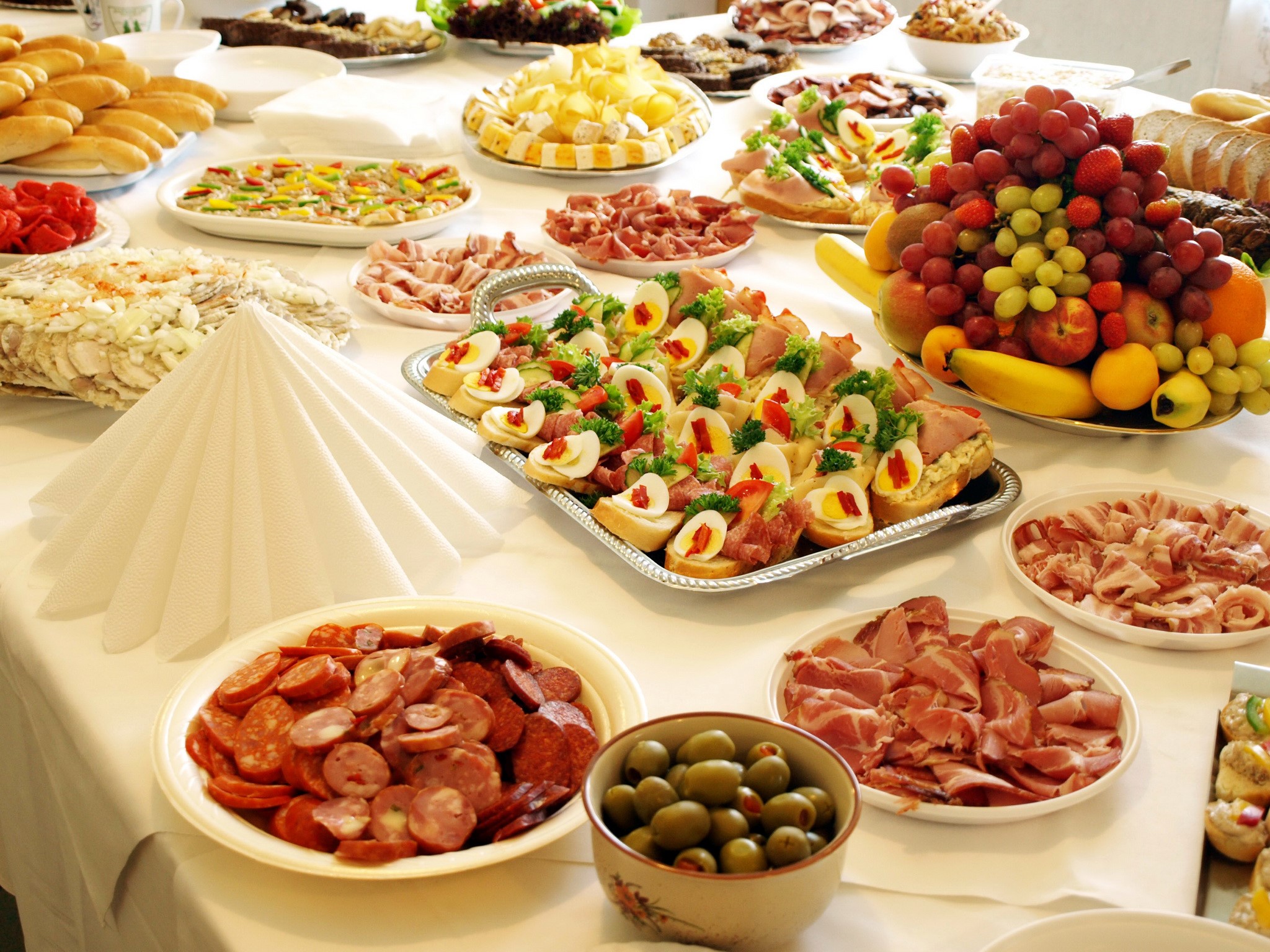 Buffet table with sausages, ham, sandwiches, and fruit HD Wallpaper