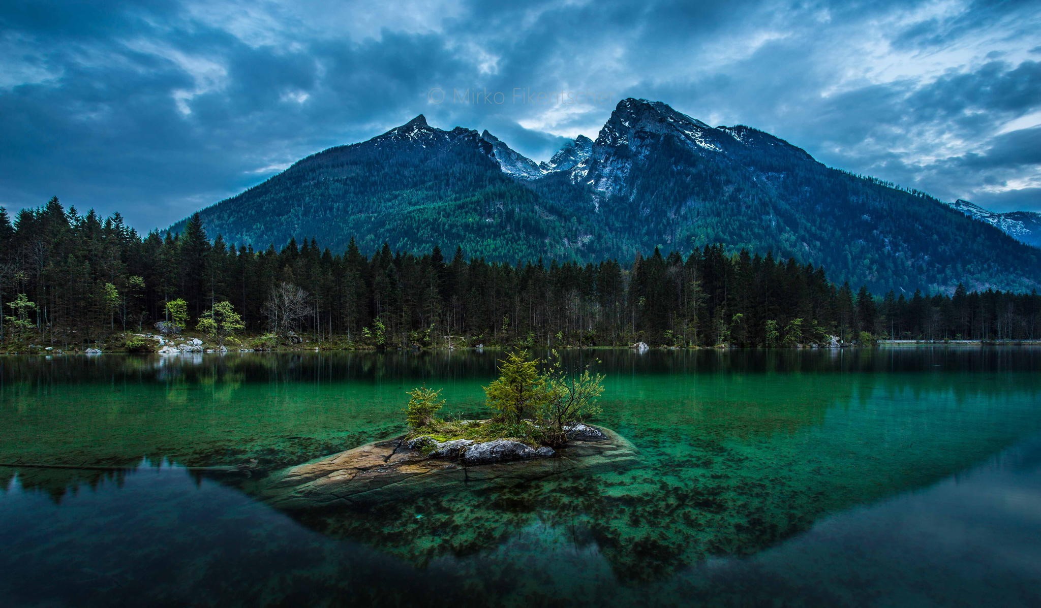 Mountains reflected in a clear lake with a small island HD Wallpaper