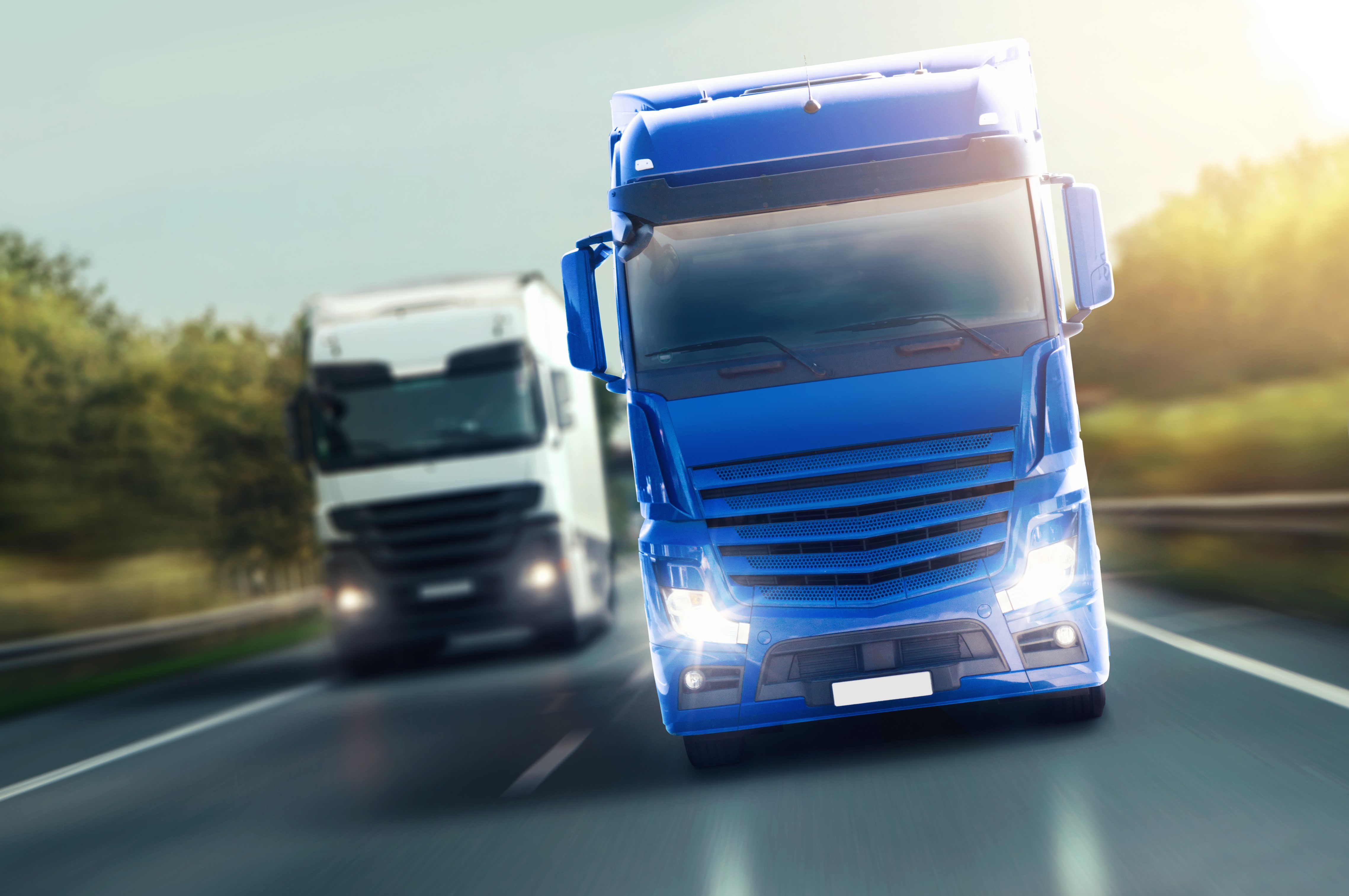 Two trucks on a highway, one blue, one white HD Wallpaper
