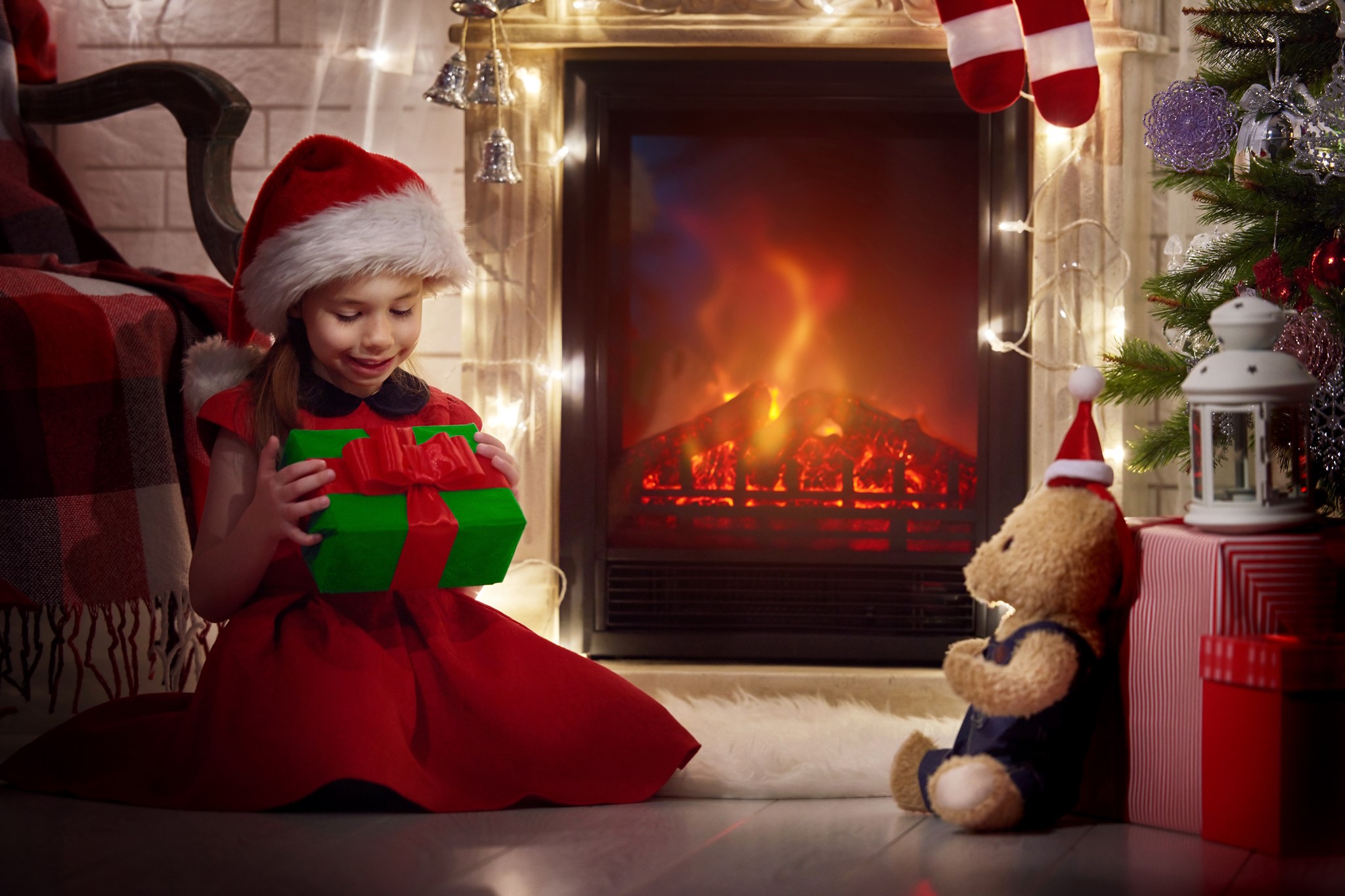 Girl in Santa hat with Christmas gift by fireplace HD Wallpaper