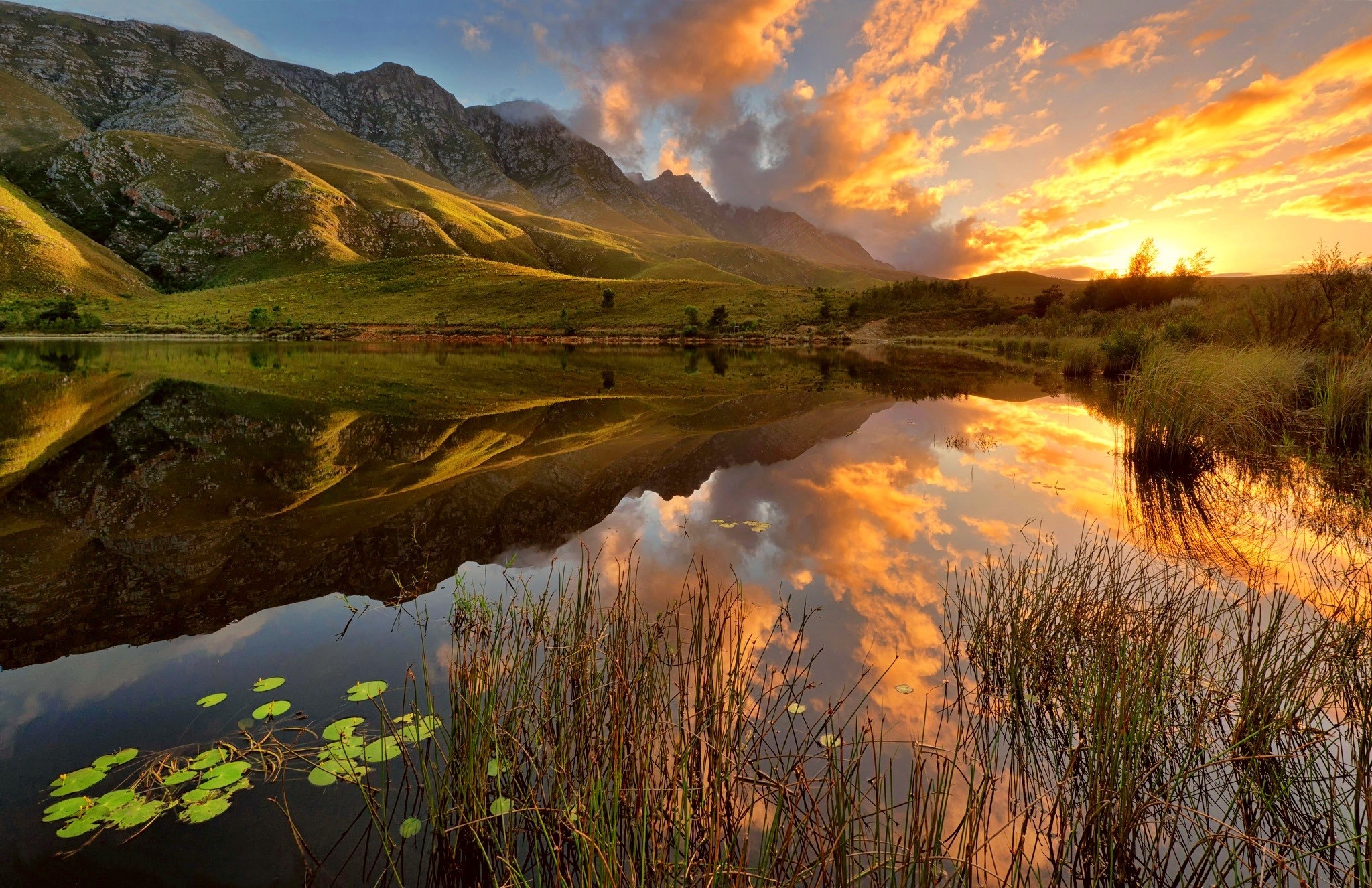 Mountains reflected in a lake at sunset HD Wallpaper