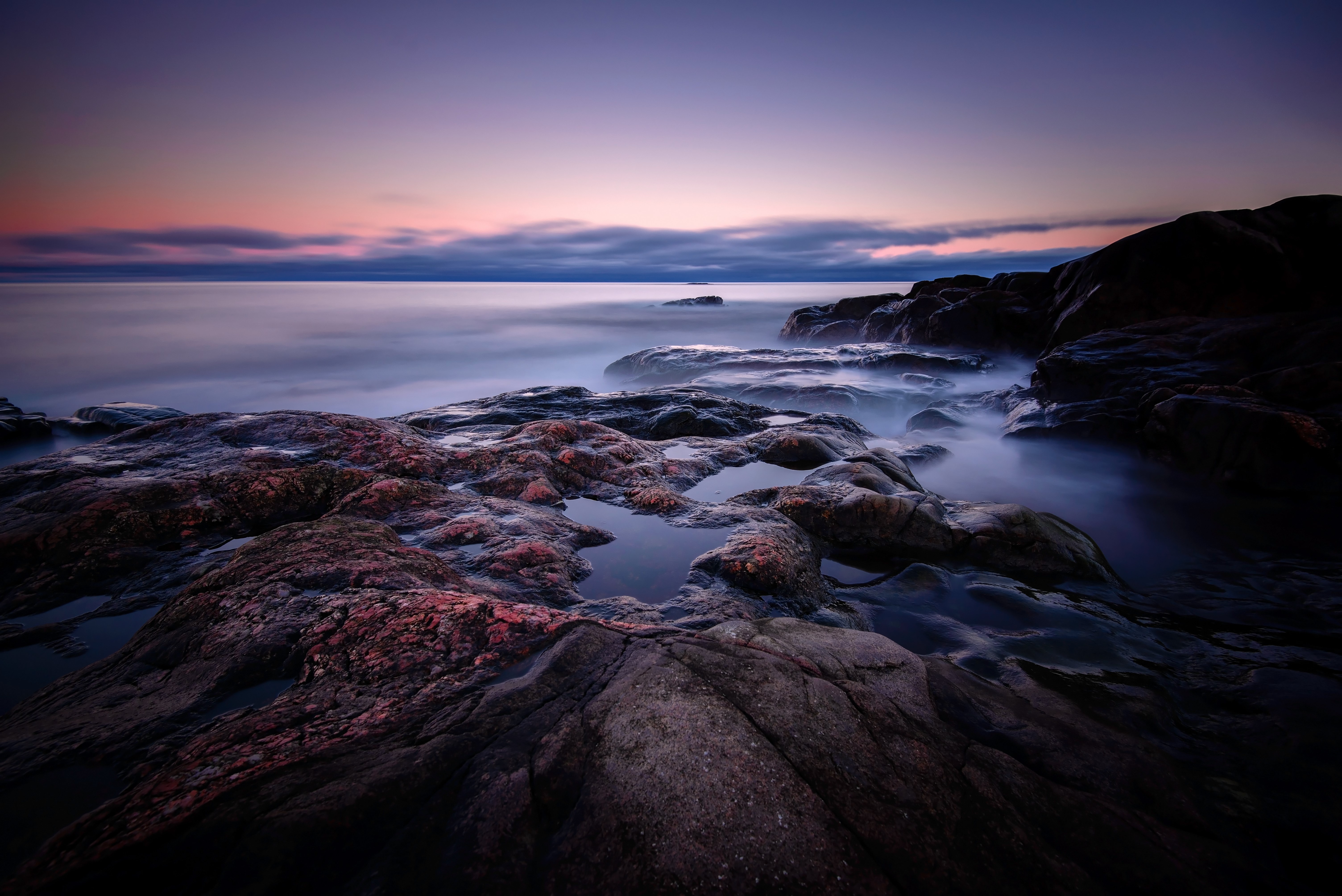 Rocky coast at twilight with misty sea HD Wallpaper