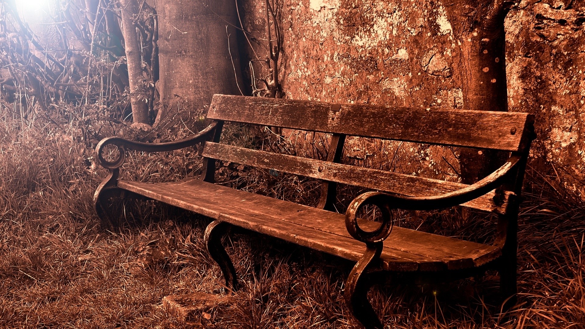 Wooden park bench by a stone wall HD Wallpaper