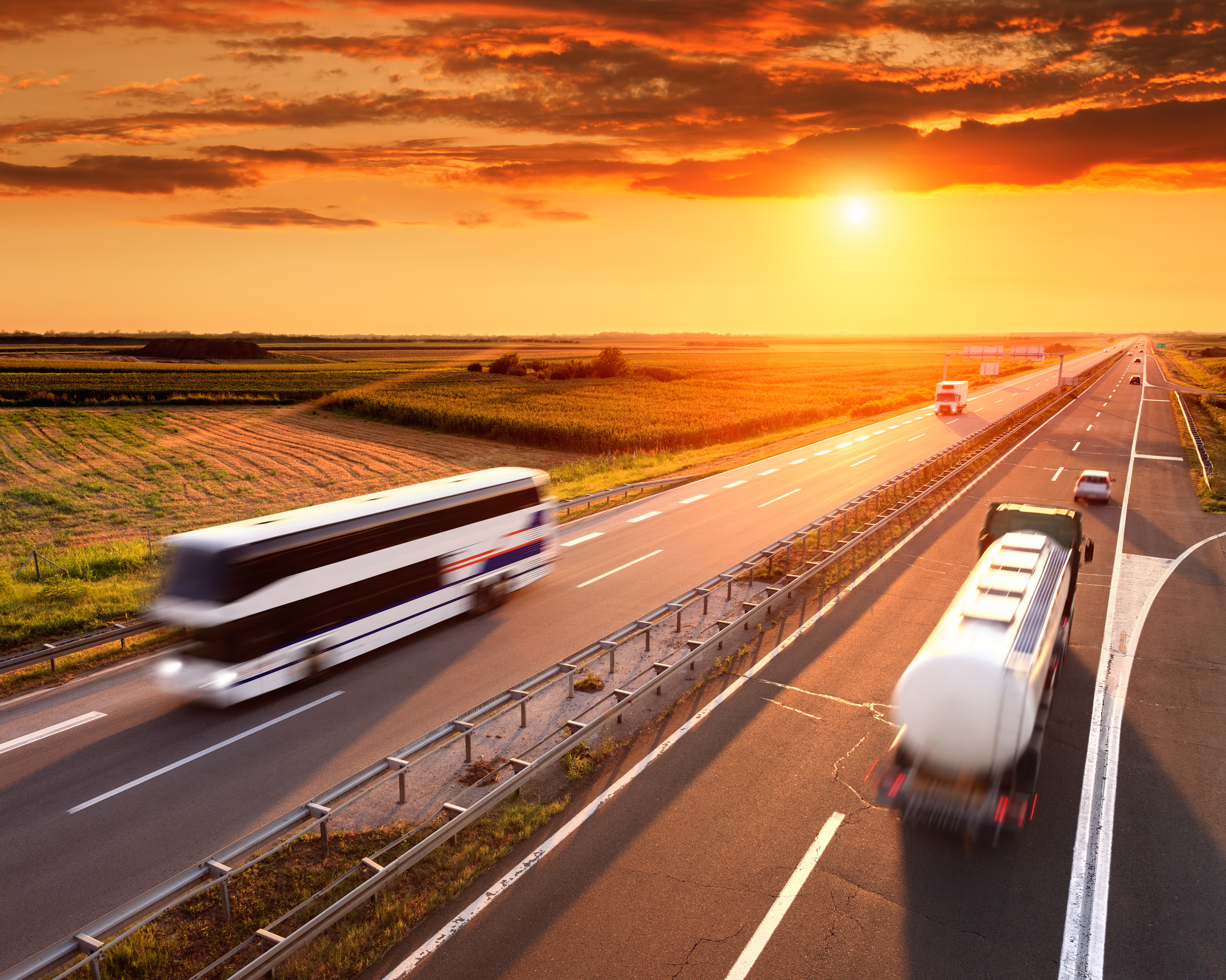 Trucks and bus on highway at sunset HD Wallpaper