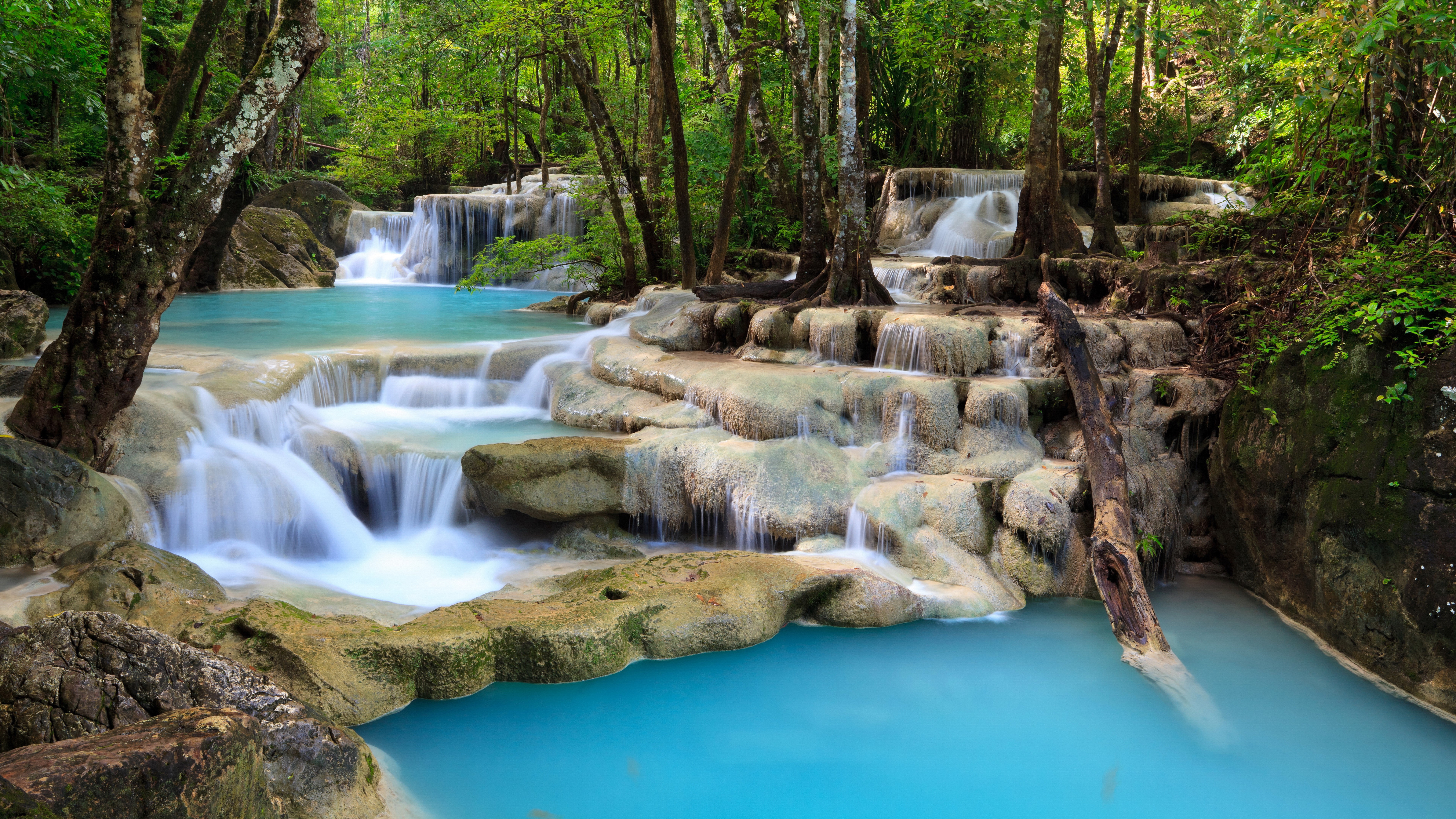 Waterfalls in a lush green forest with blue water HD Wallpaper