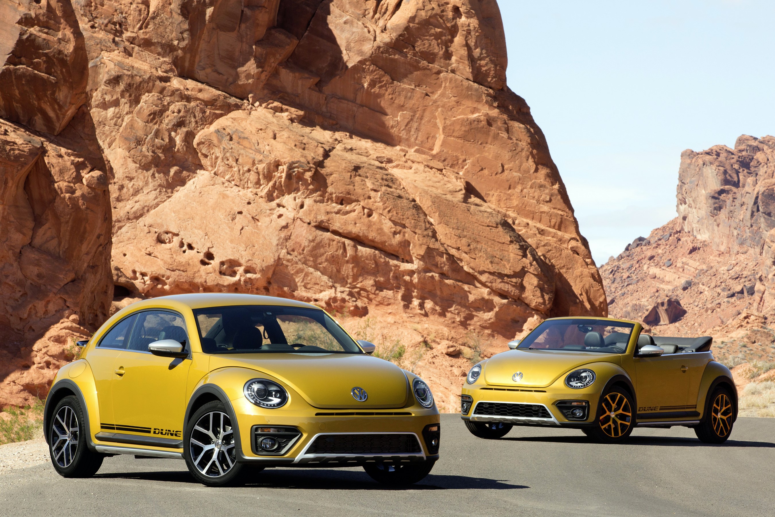 Two yellow Volkswagen Beetle Dune cars in a desert landscape HD Wallpaper