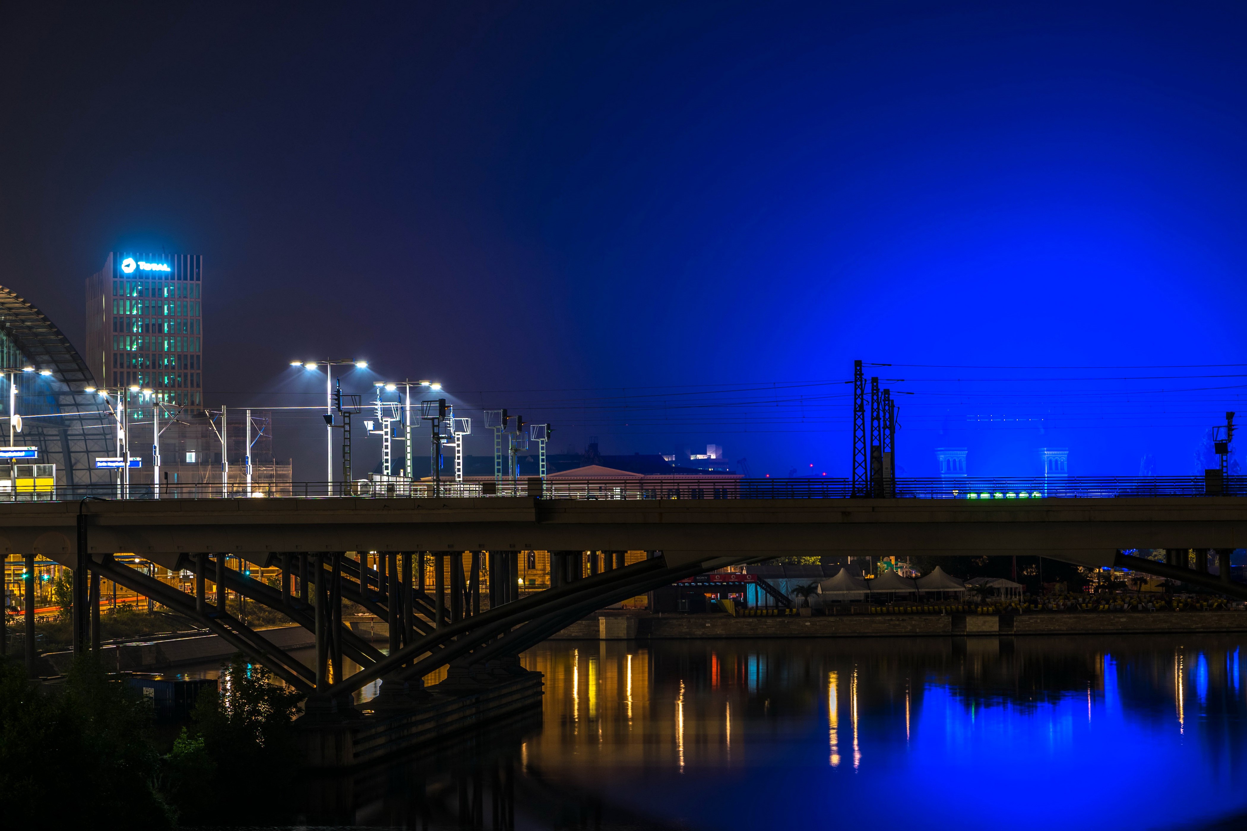 Bridge over river at night with city lights HD Wallpaper