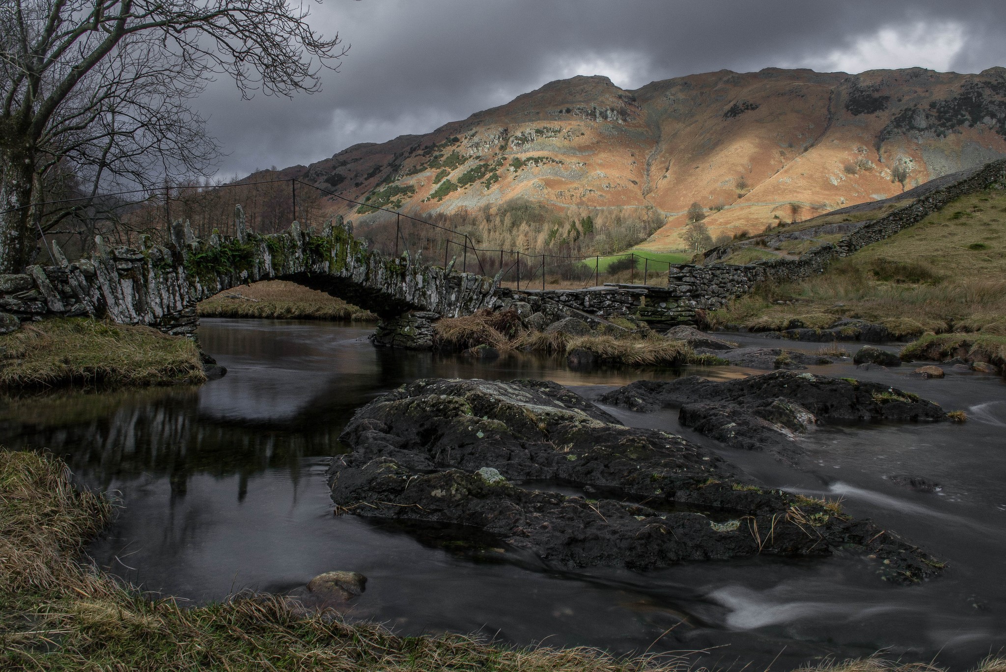 Stone bridge over a river with mountains in the background HD Wallpaper