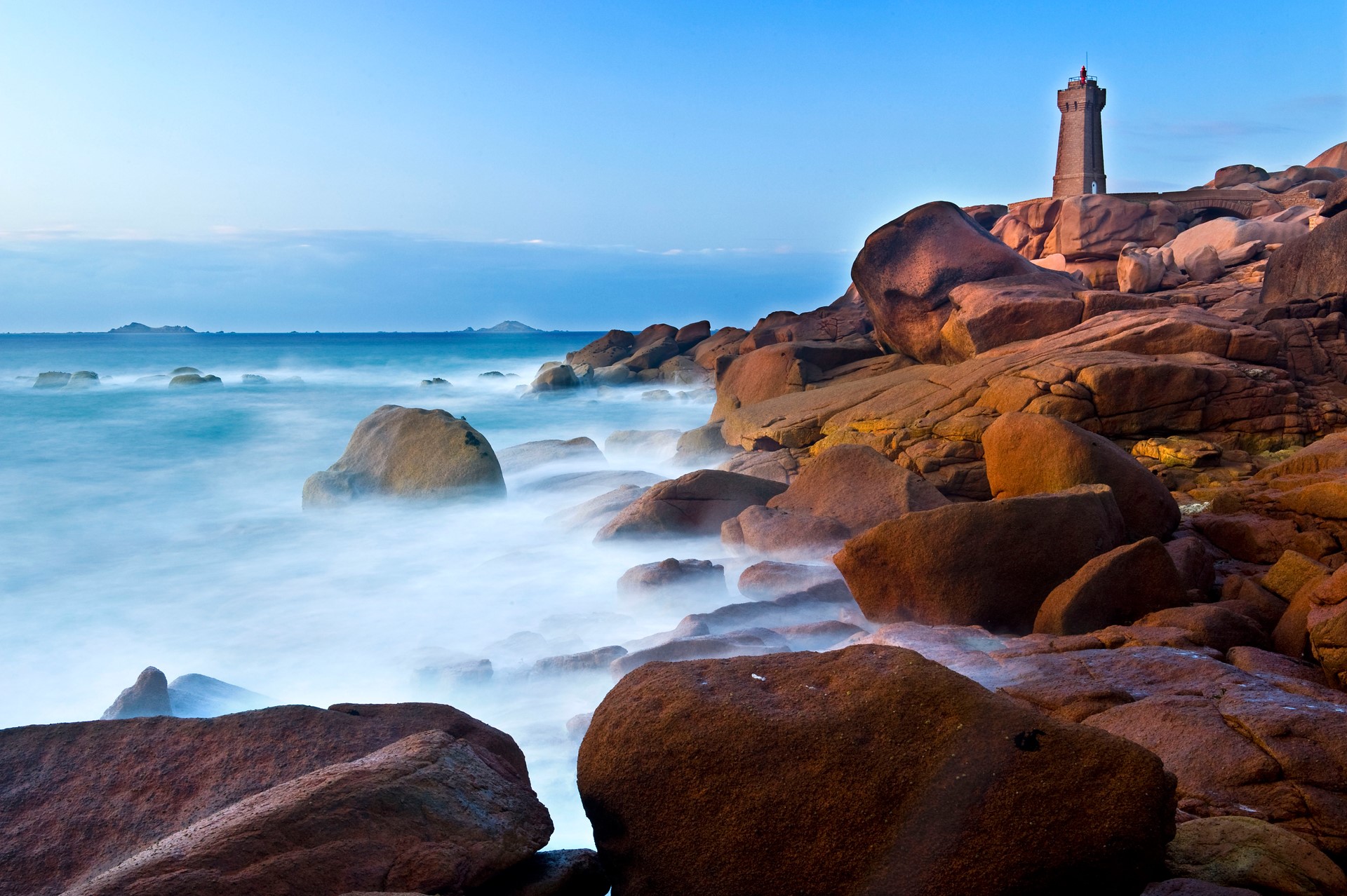 Lighthouse on a rocky coast with the sea HD Wallpaper