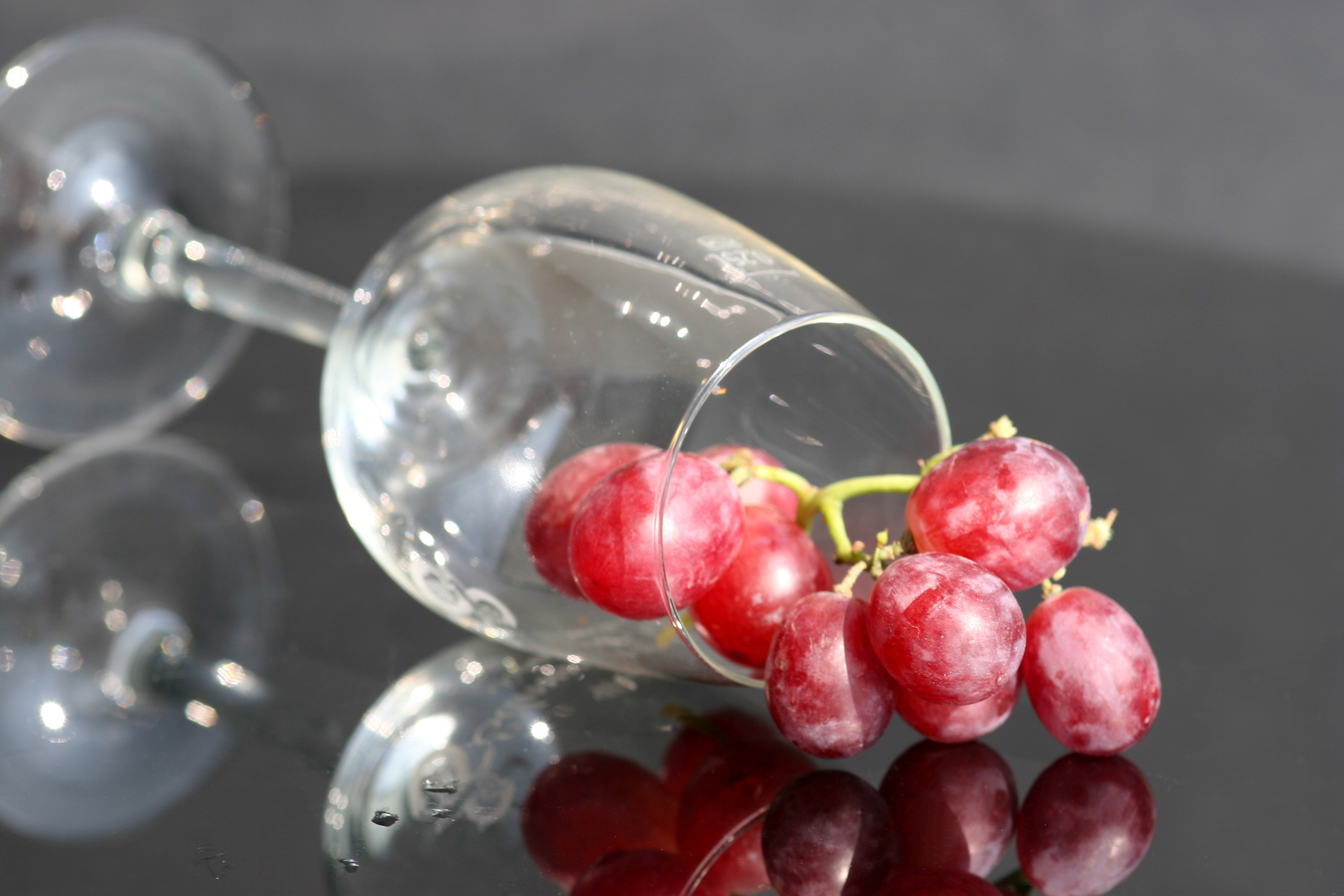 Red grapes spilling from a wine glass HD Wallpaper