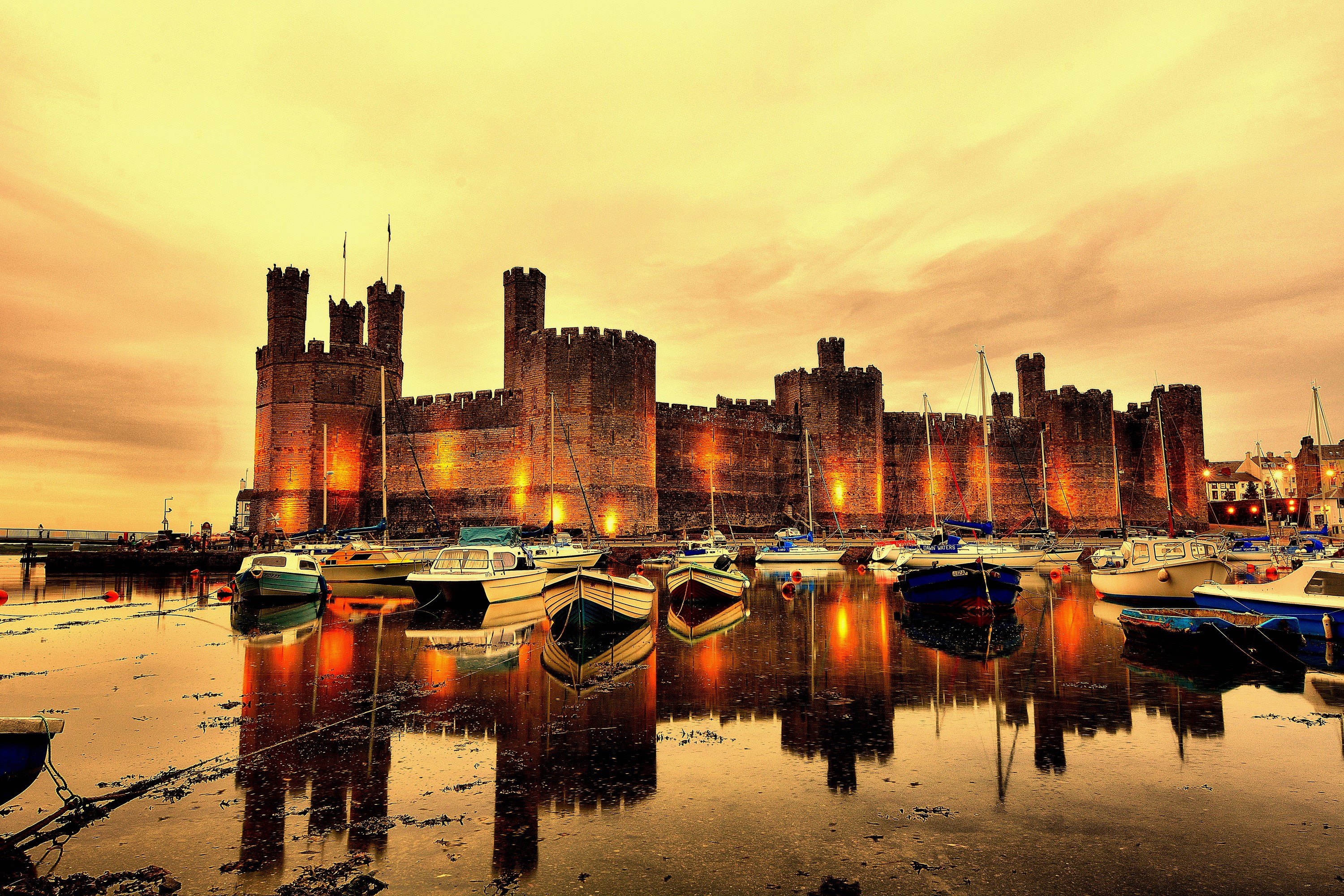 Caernarfon Castle and boats in a harbor at dusk HD Wallpaper