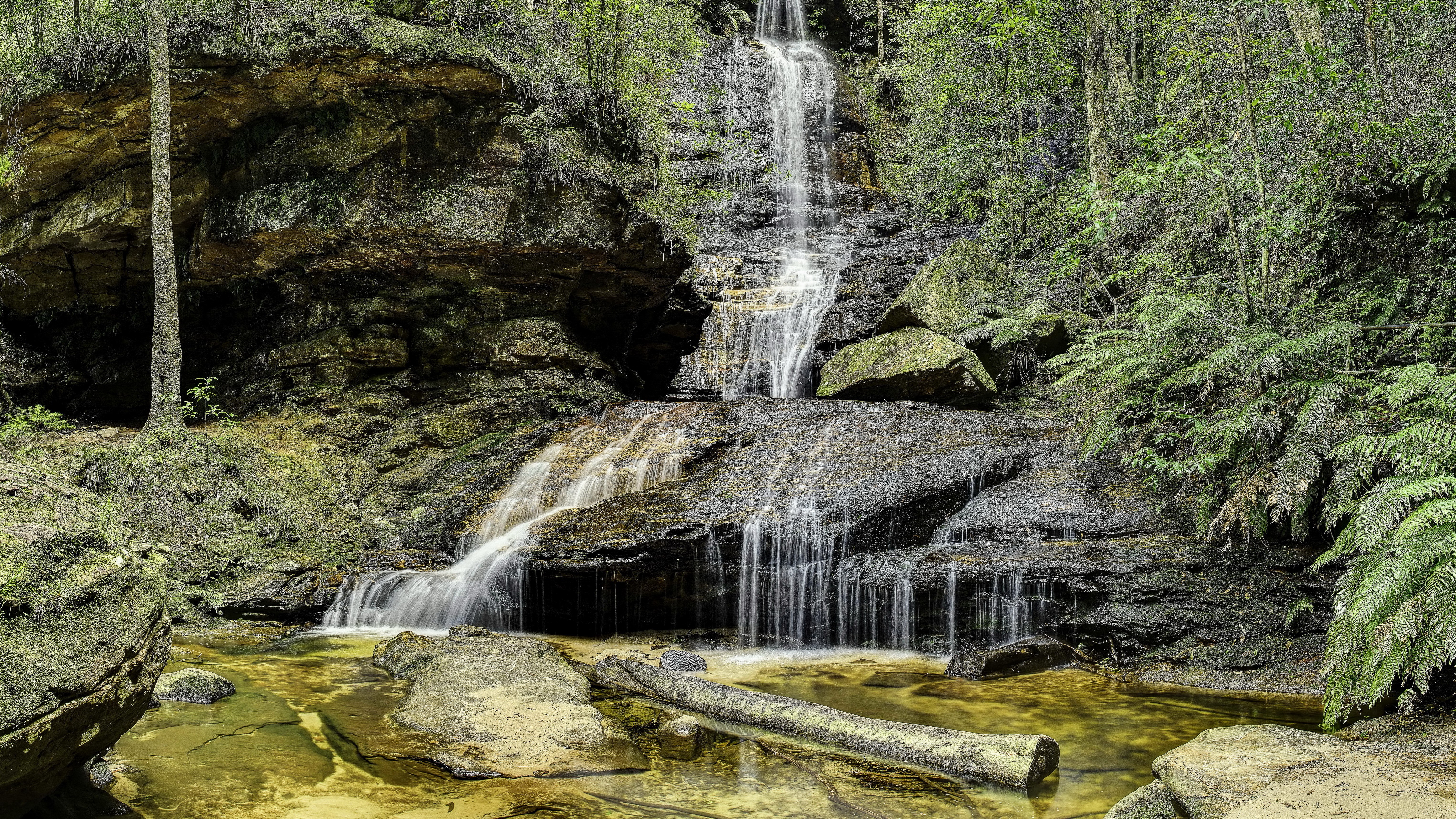 Waterfall cascading over rocks in a forest HD Wallpaper