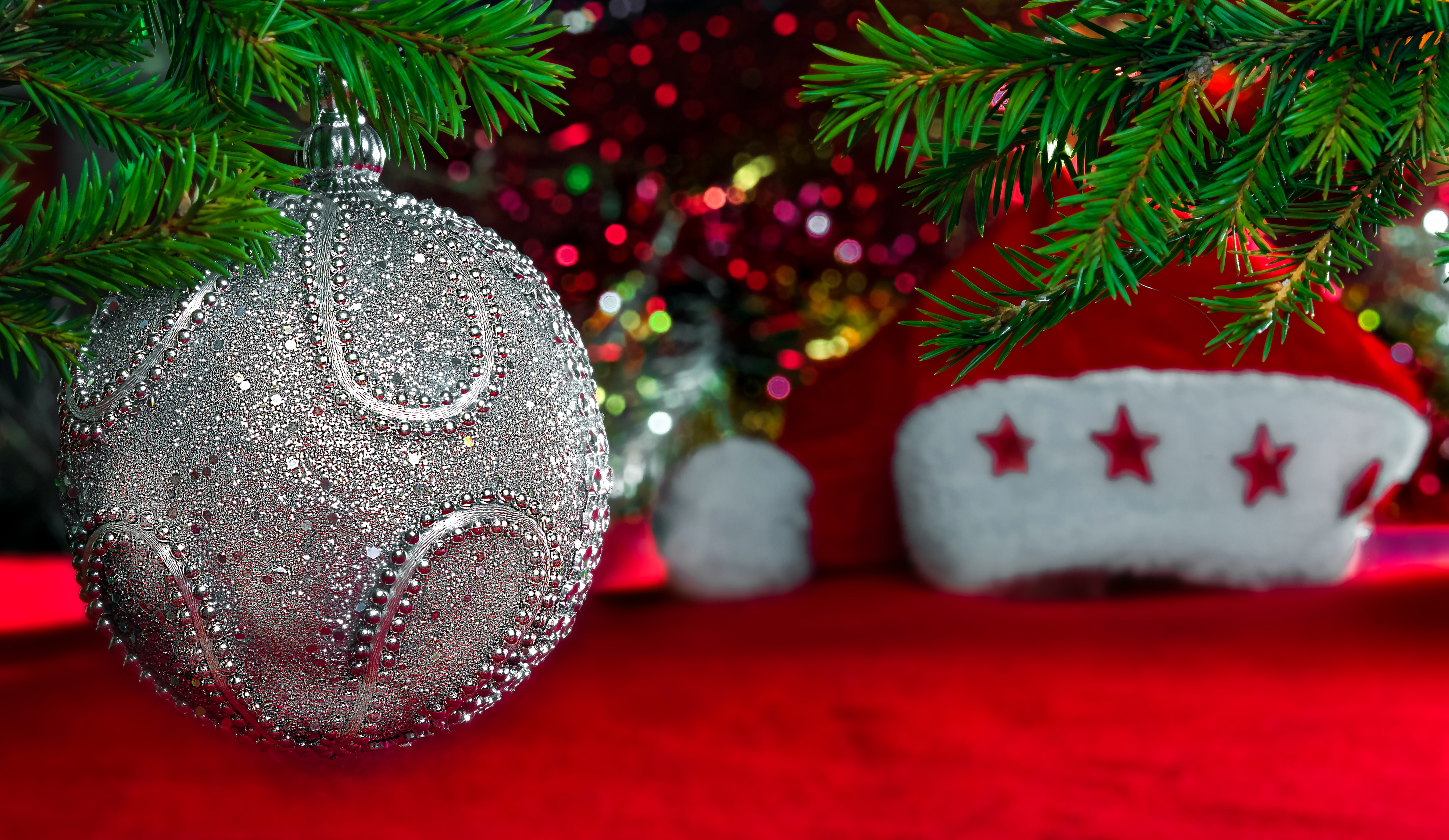 Christmas ornament and Santa hat on a red surface HD Wallpaper