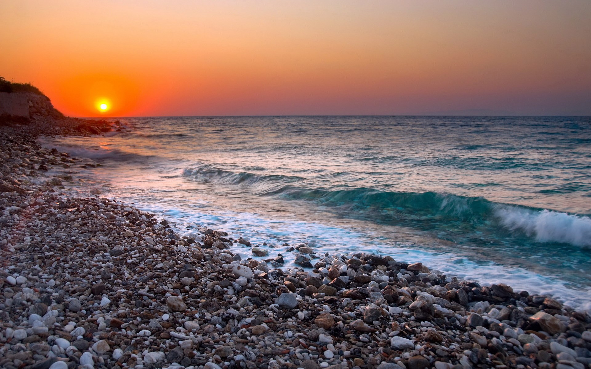 Sunset over a rocky beach with waves HD Wallpaper