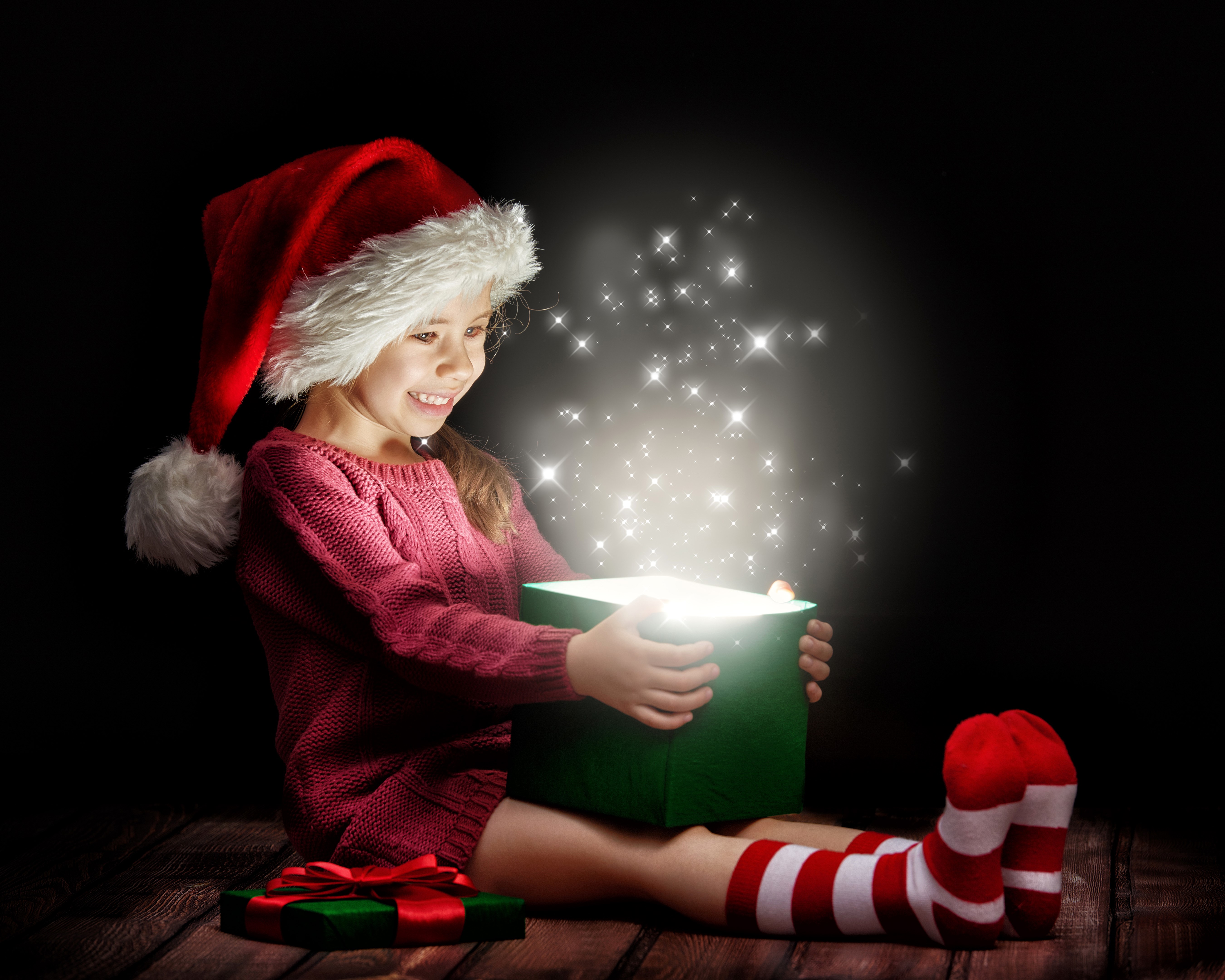 Girl in Santa hat opening a magical Christmas gift HD Wallpaper