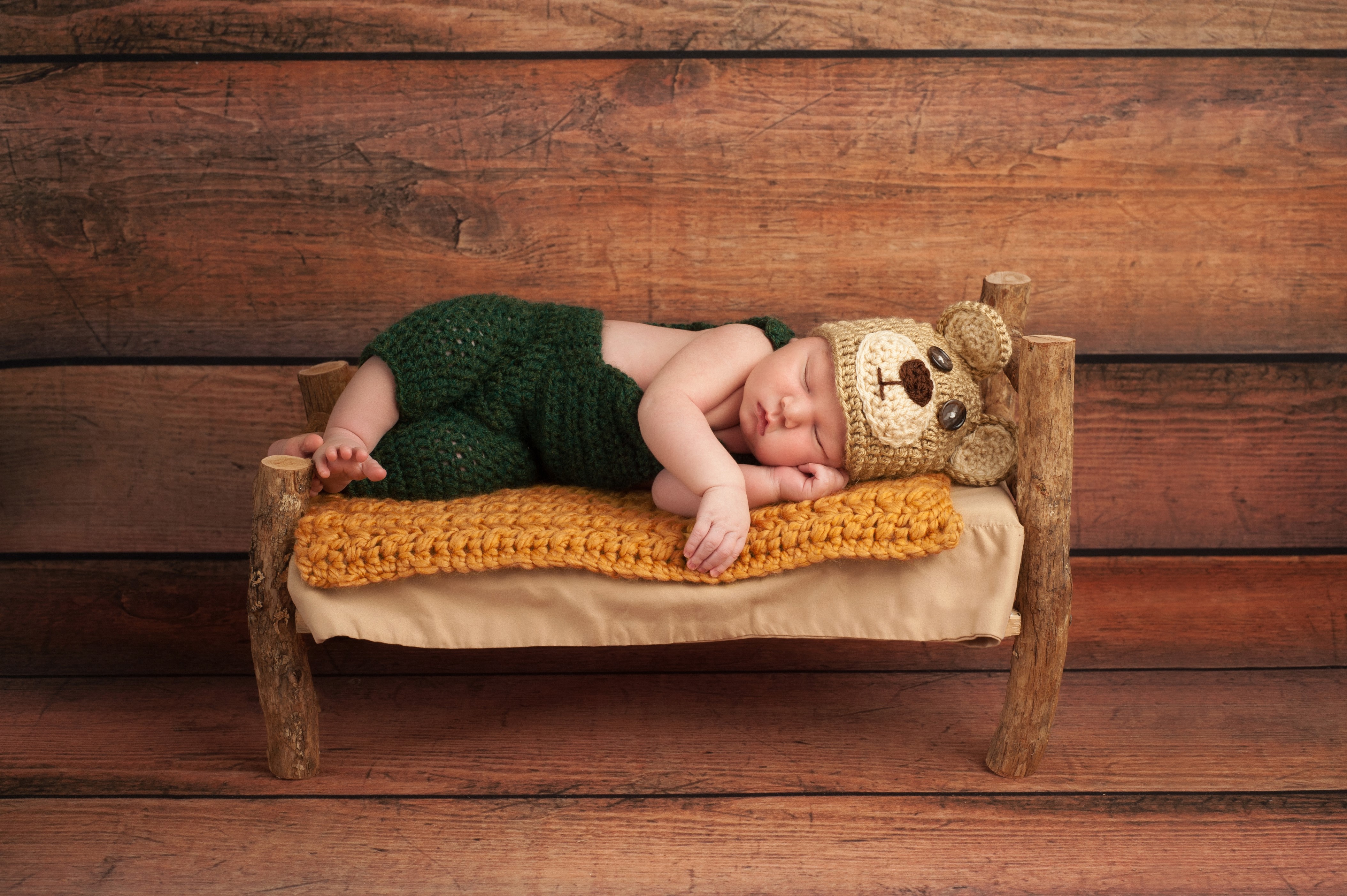 Baby in Bear Hat Sleeping on a Wooden Bed HD Wallpaper
