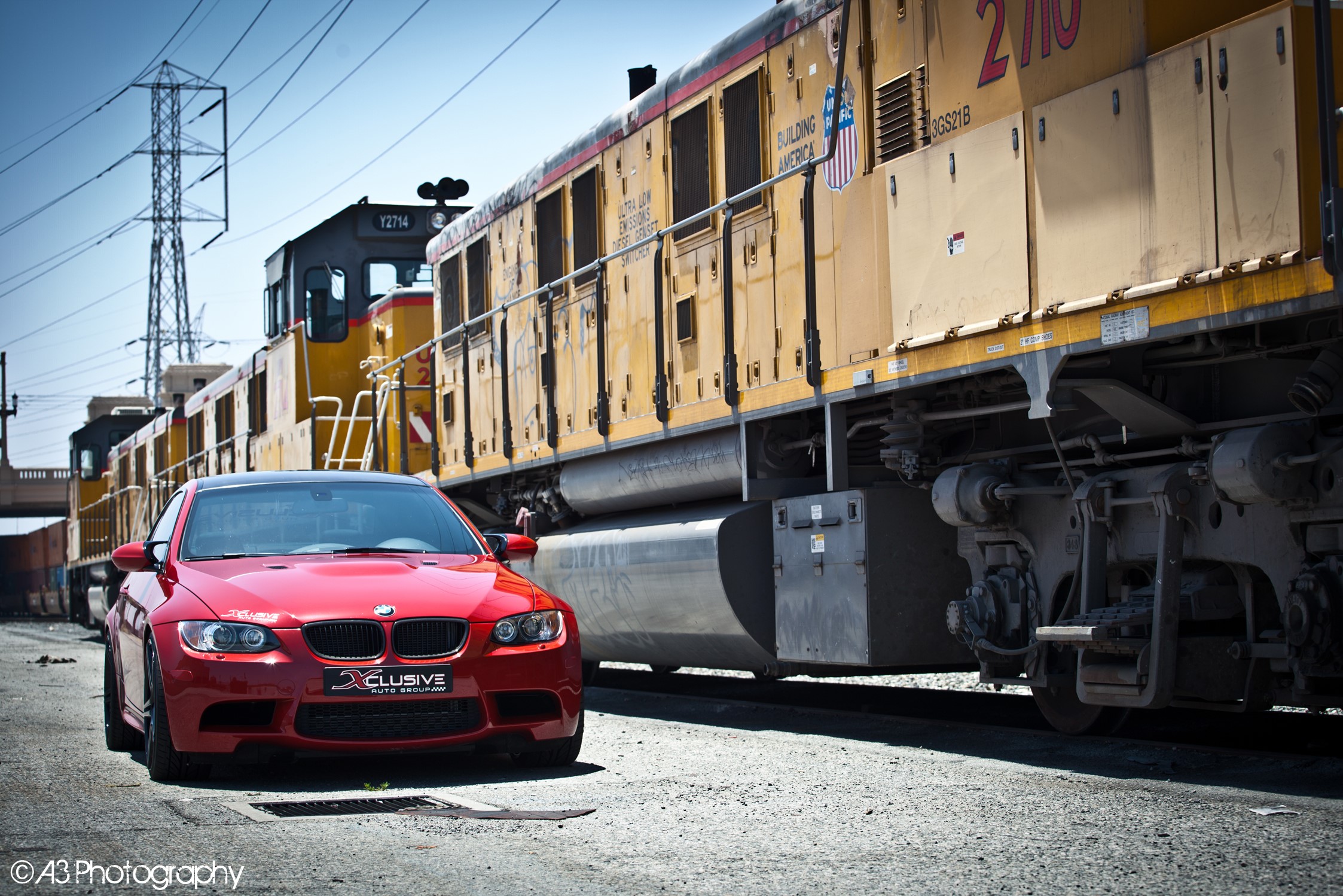 Red BMW M3 parked next to a yellow train HD Wallpaper