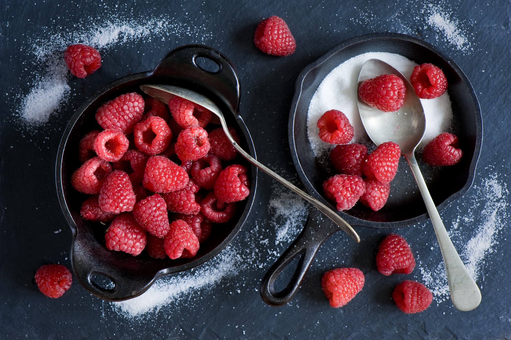 Raspberries and sugar in cast iron dishes with spoons HD Wallpaper