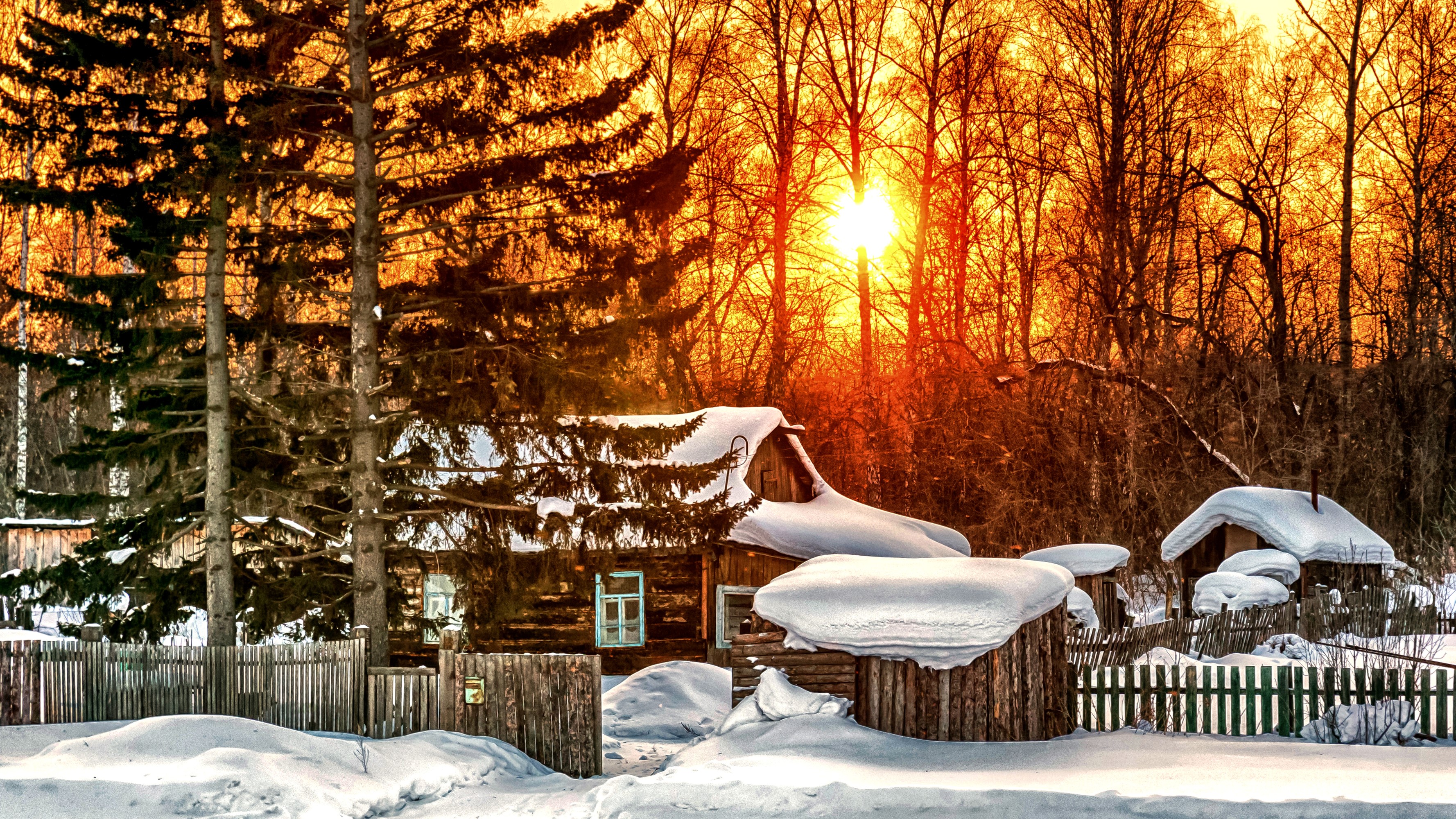 Winter scene with snow-covered houses and trees at sunset HD Wallpaper