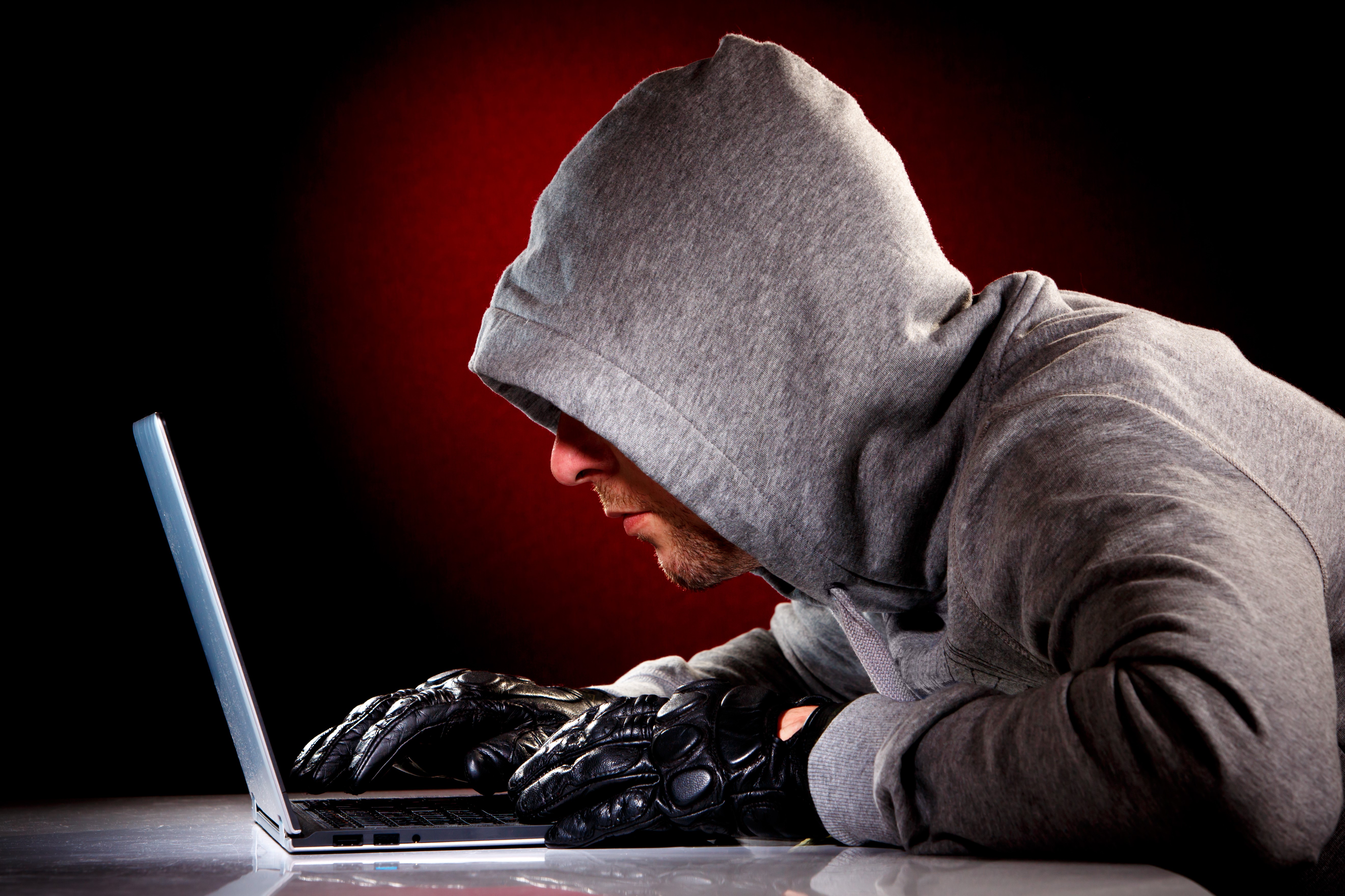 Man in hoodie and gloves using laptop HD Wallpaper