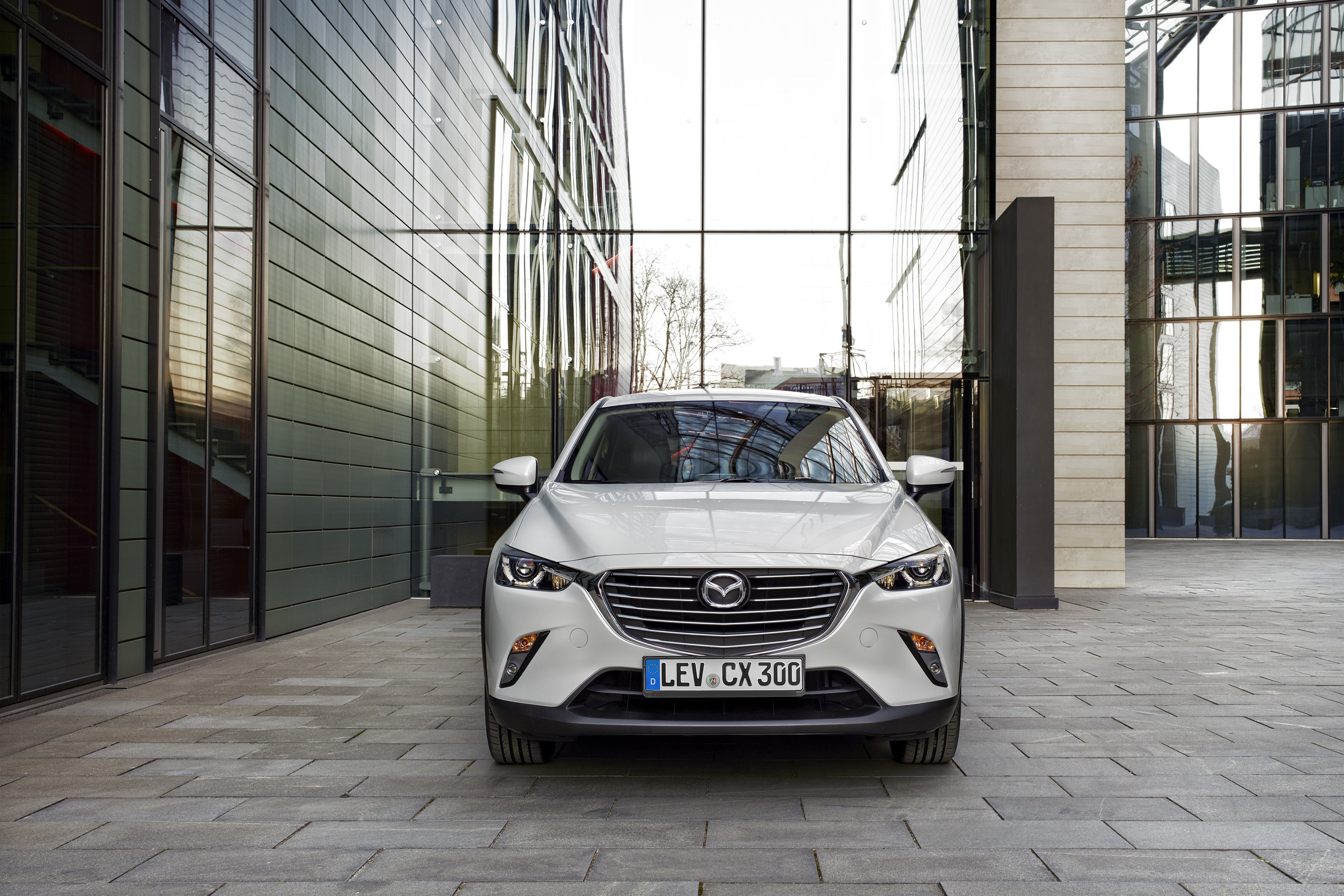 White Mazda CX-3 parked in front of a modern building HD Wallpaper