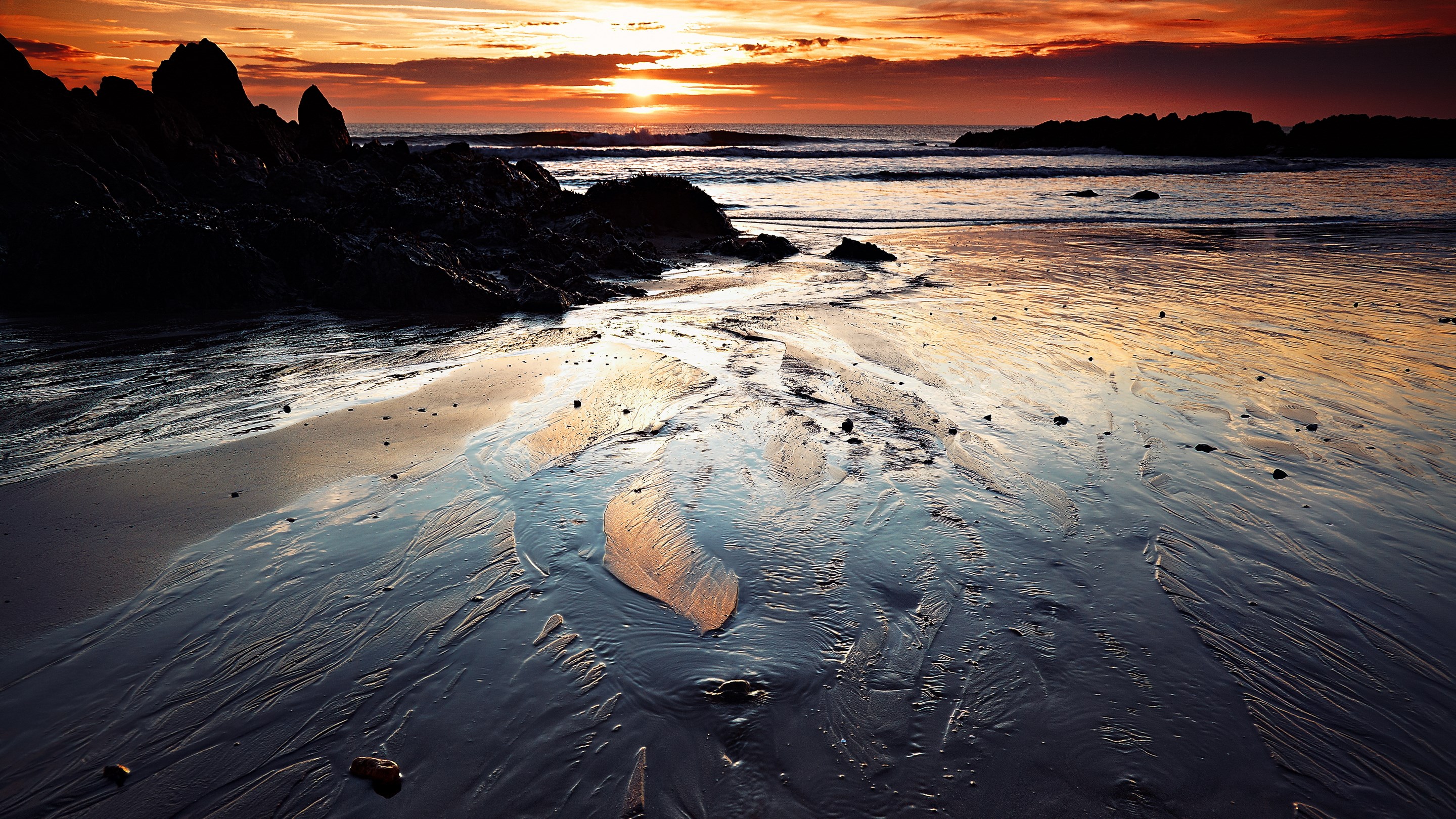 Sunset over a rocky beach with wet sand HD Wallpaper
