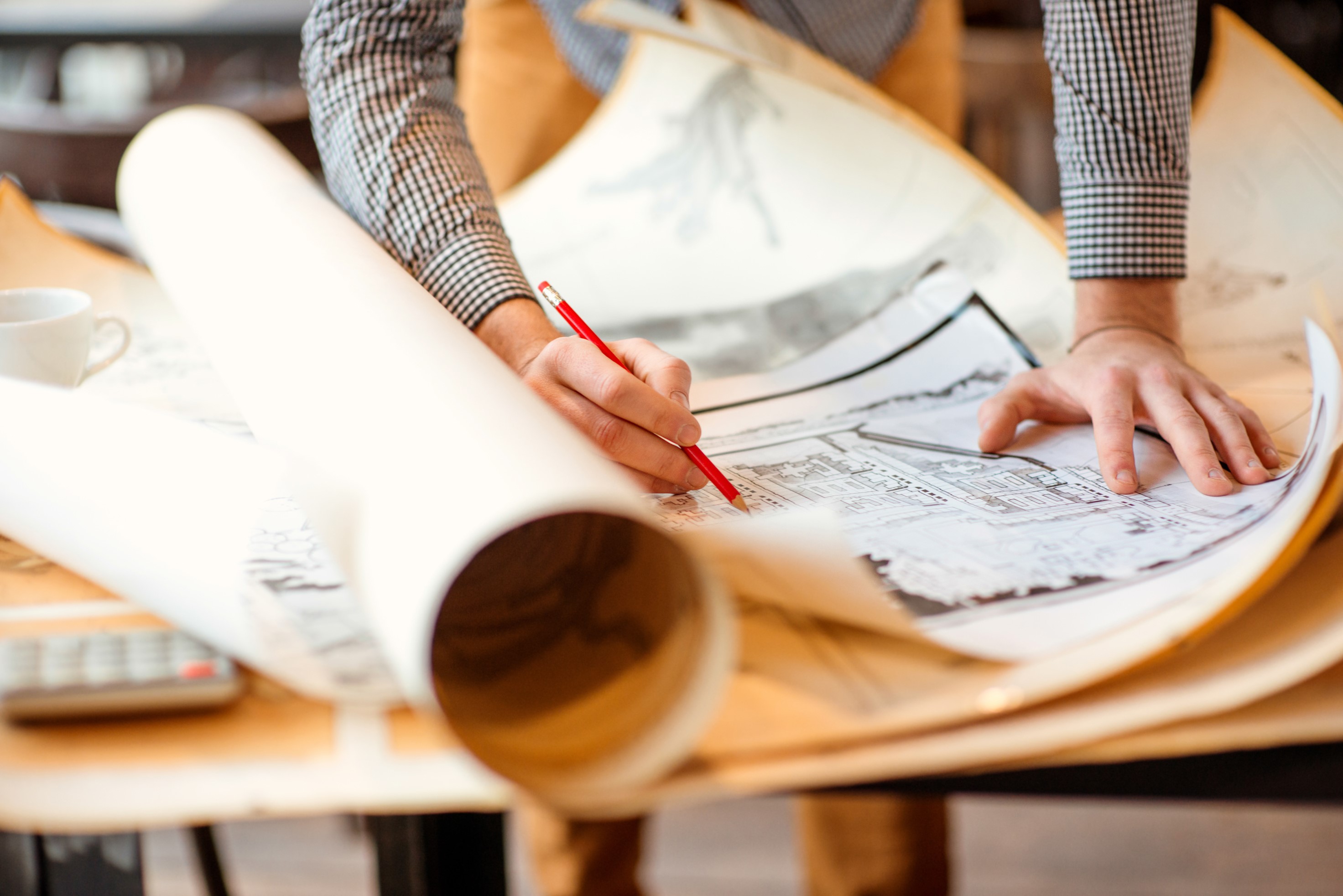 Architect reviewing blueprints with pencil and calculator HD Wallpaper