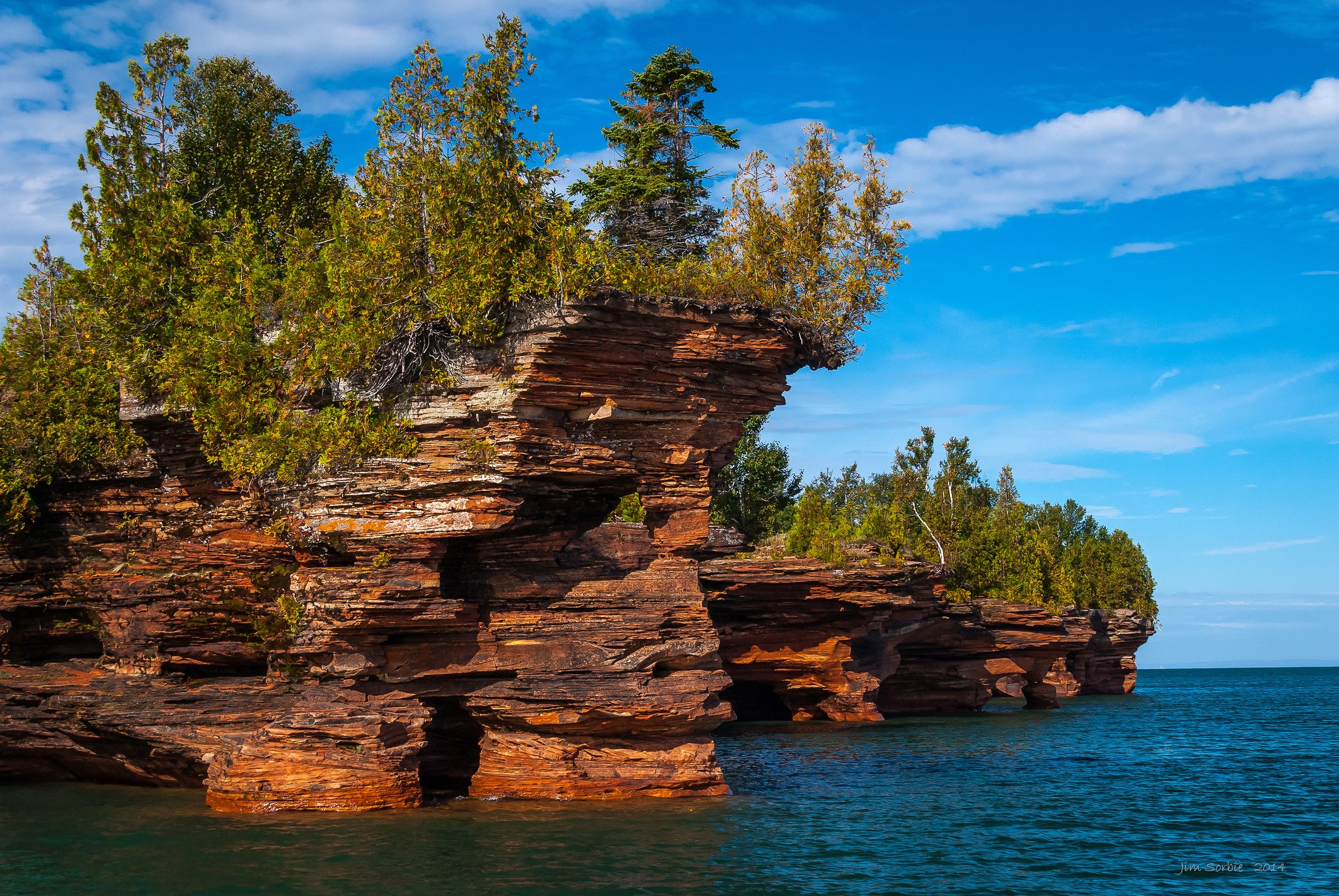 Red rock formations with trees on the water HD Wallpaper