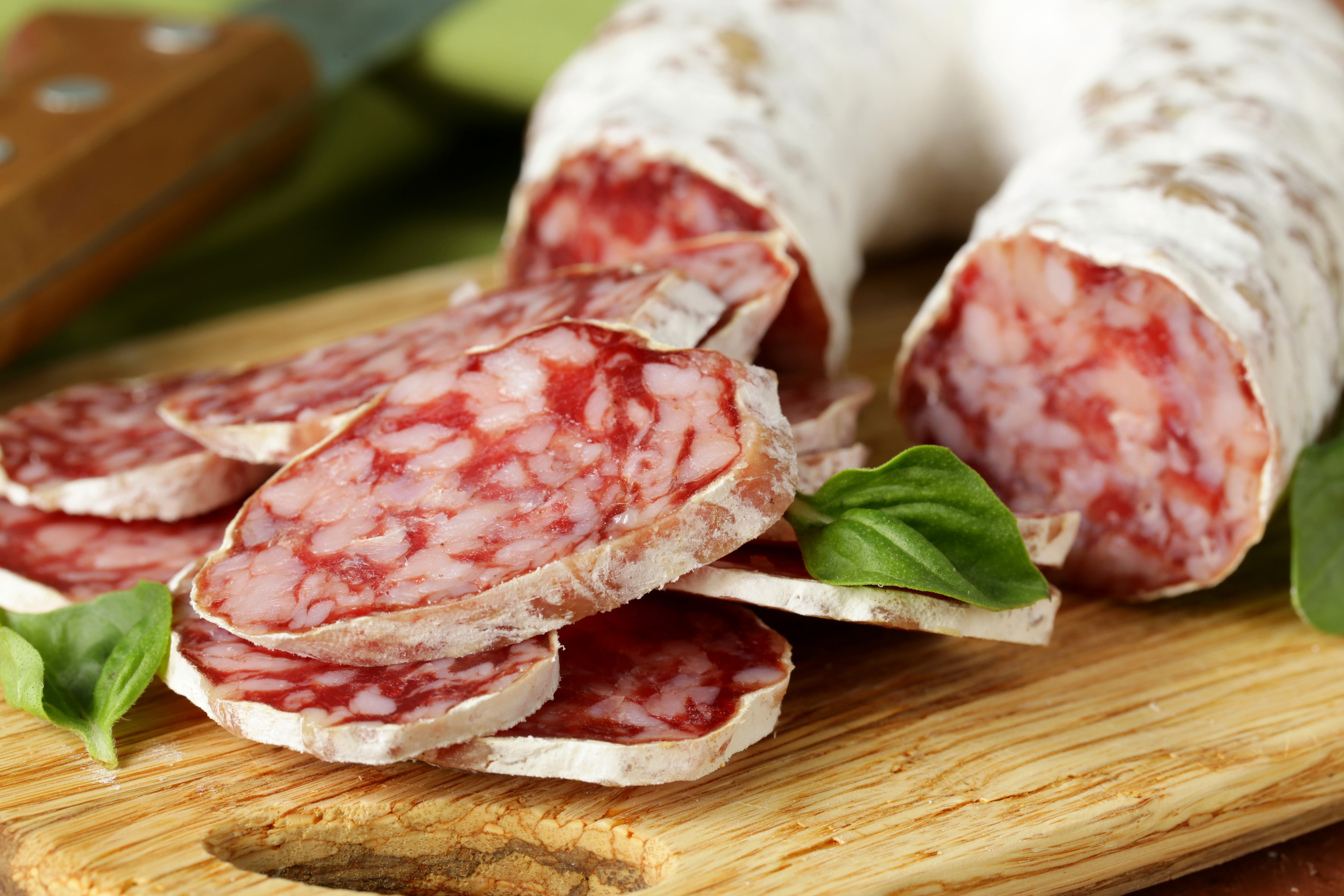 Sliced dry-cured sausage with basil leaves HD Wallpaper