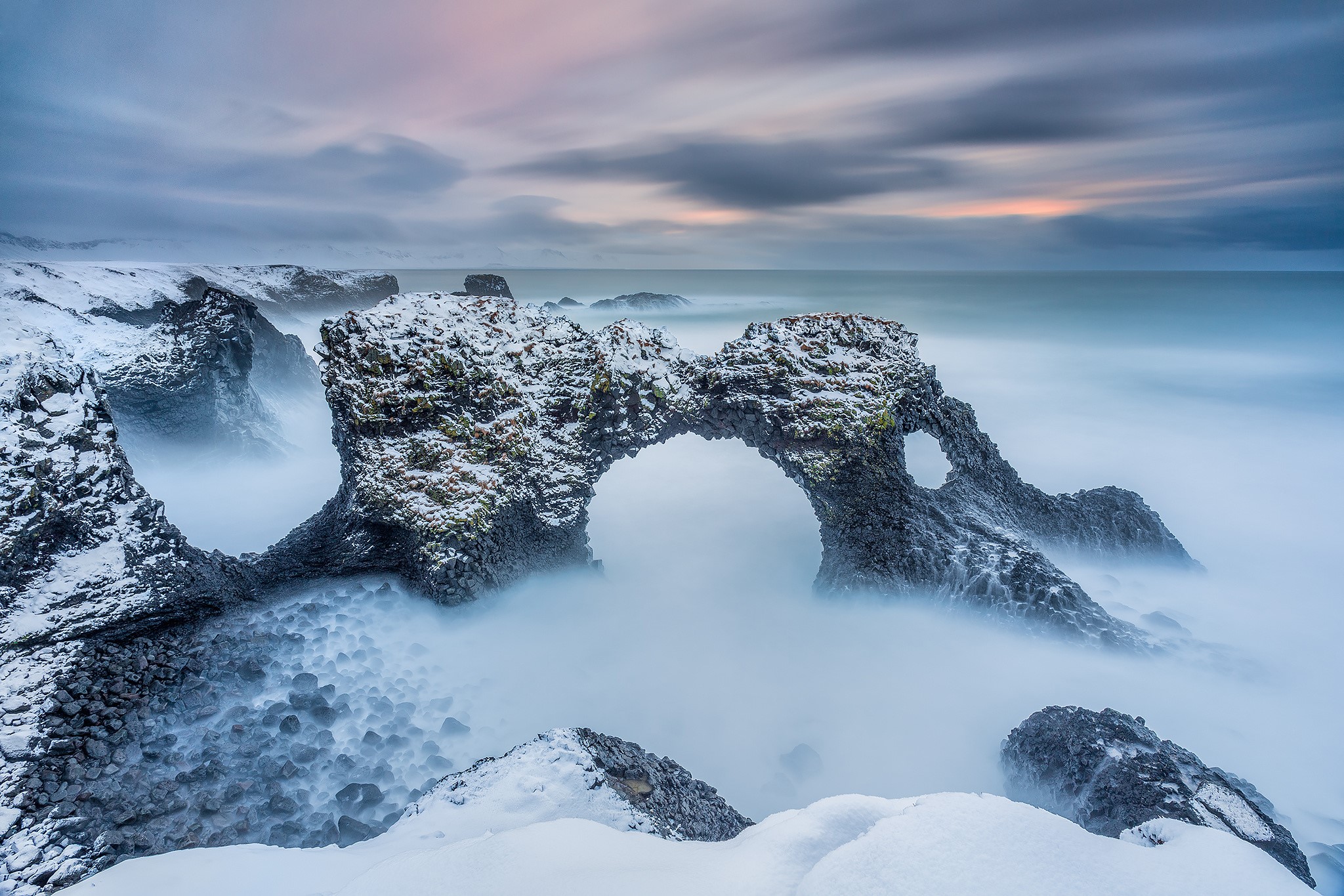 Snow-covered rock arch in the sea in Iceland during winter HD Wallpaper