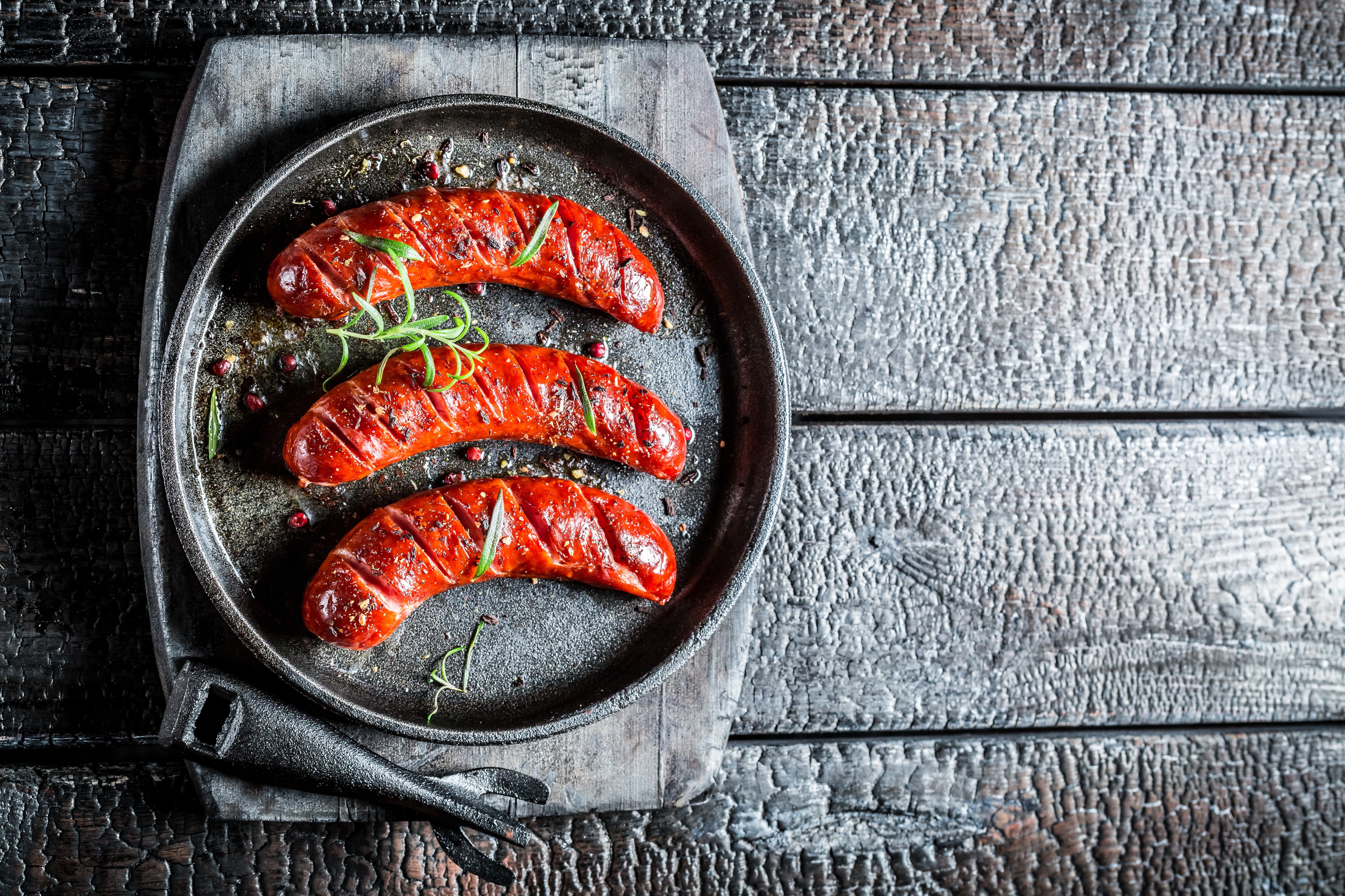 Three grilled sausages with rosemary on a pan HD Wallpaper