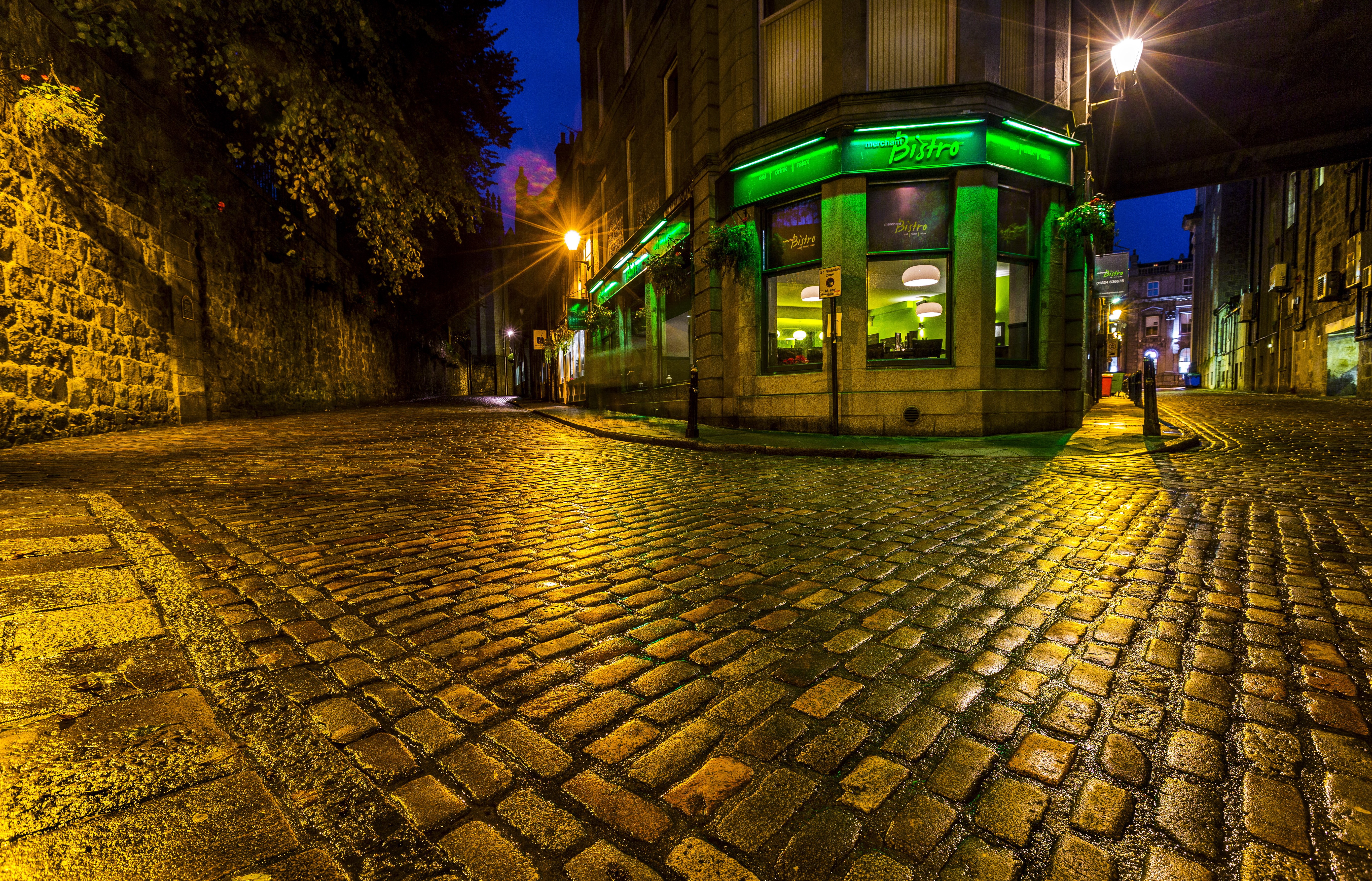 Cobblestone street at night with a bistro in Scotland HD Wallpaper