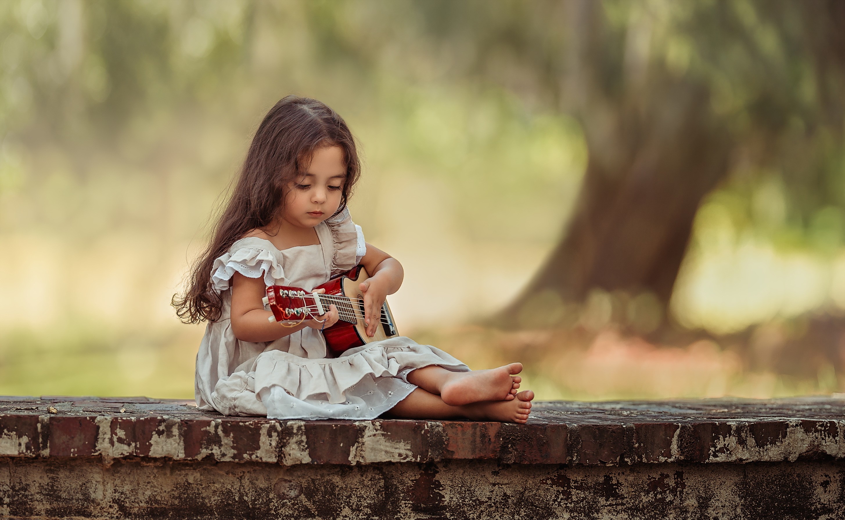 Young girl playing a guitar outdoors HD Wallpaper