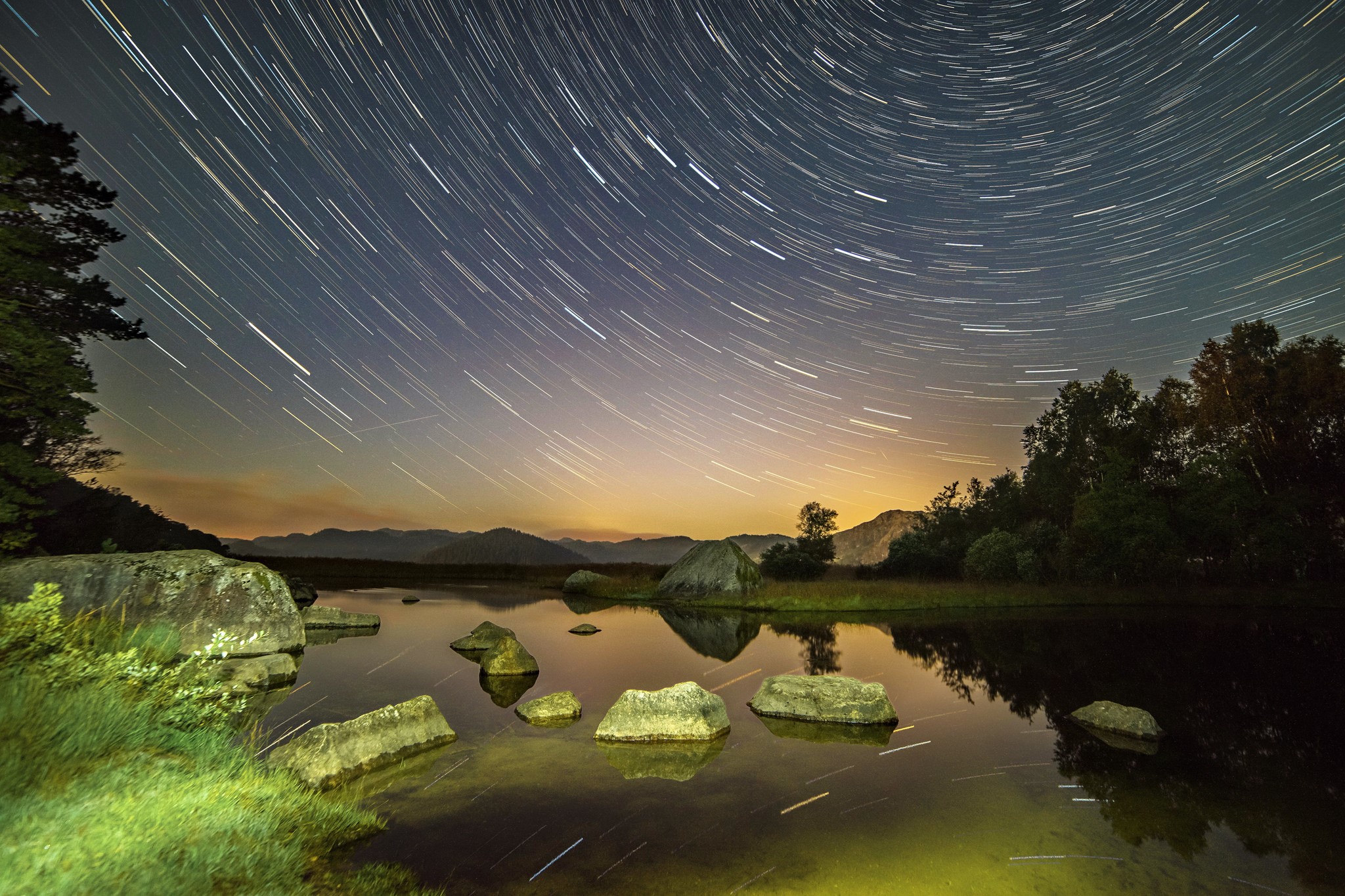 Star trails over a rocky lake at night HD Wallpaper