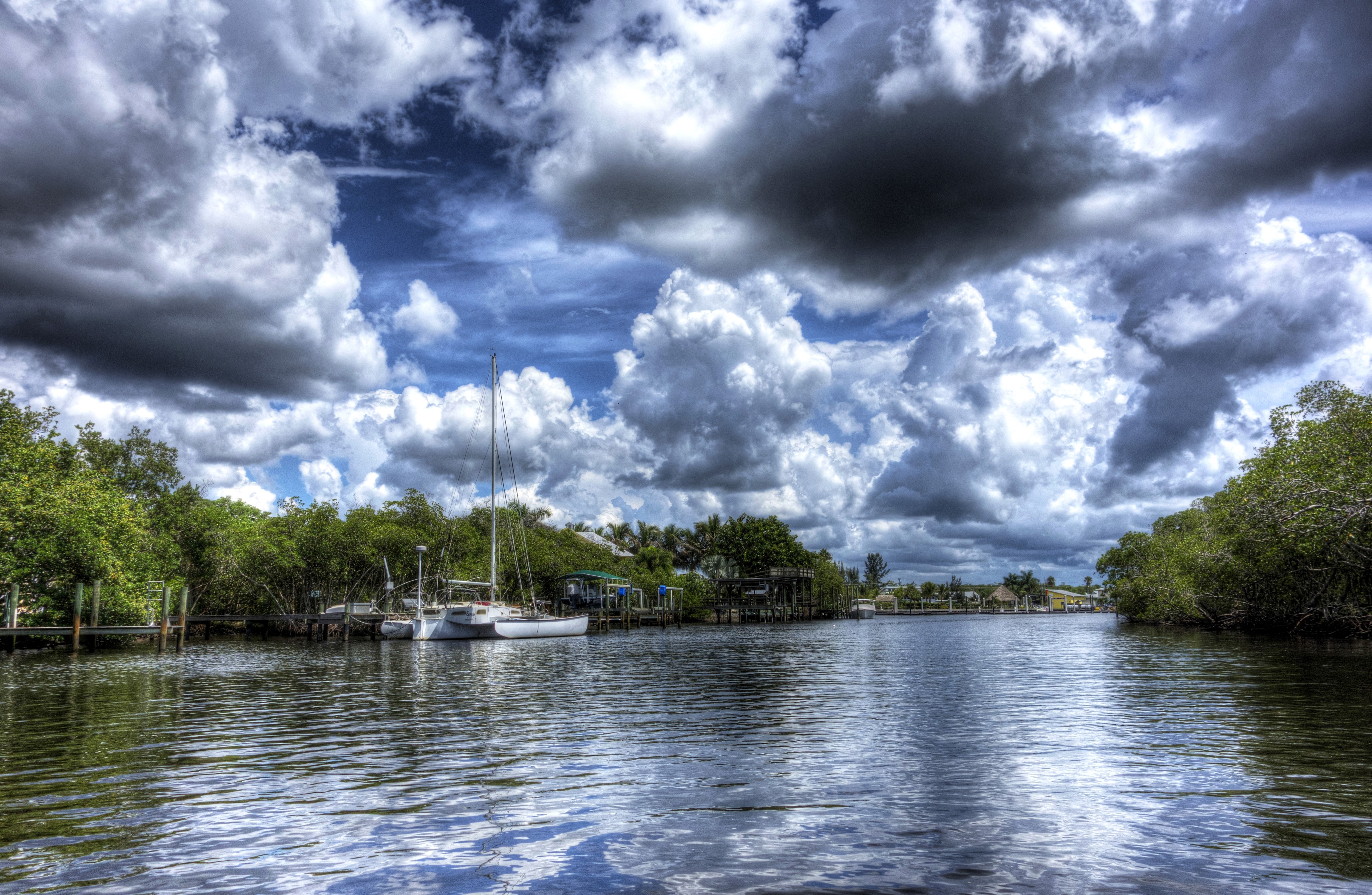 Boats docked in a canal with dramatic clouds HD Wallpaper