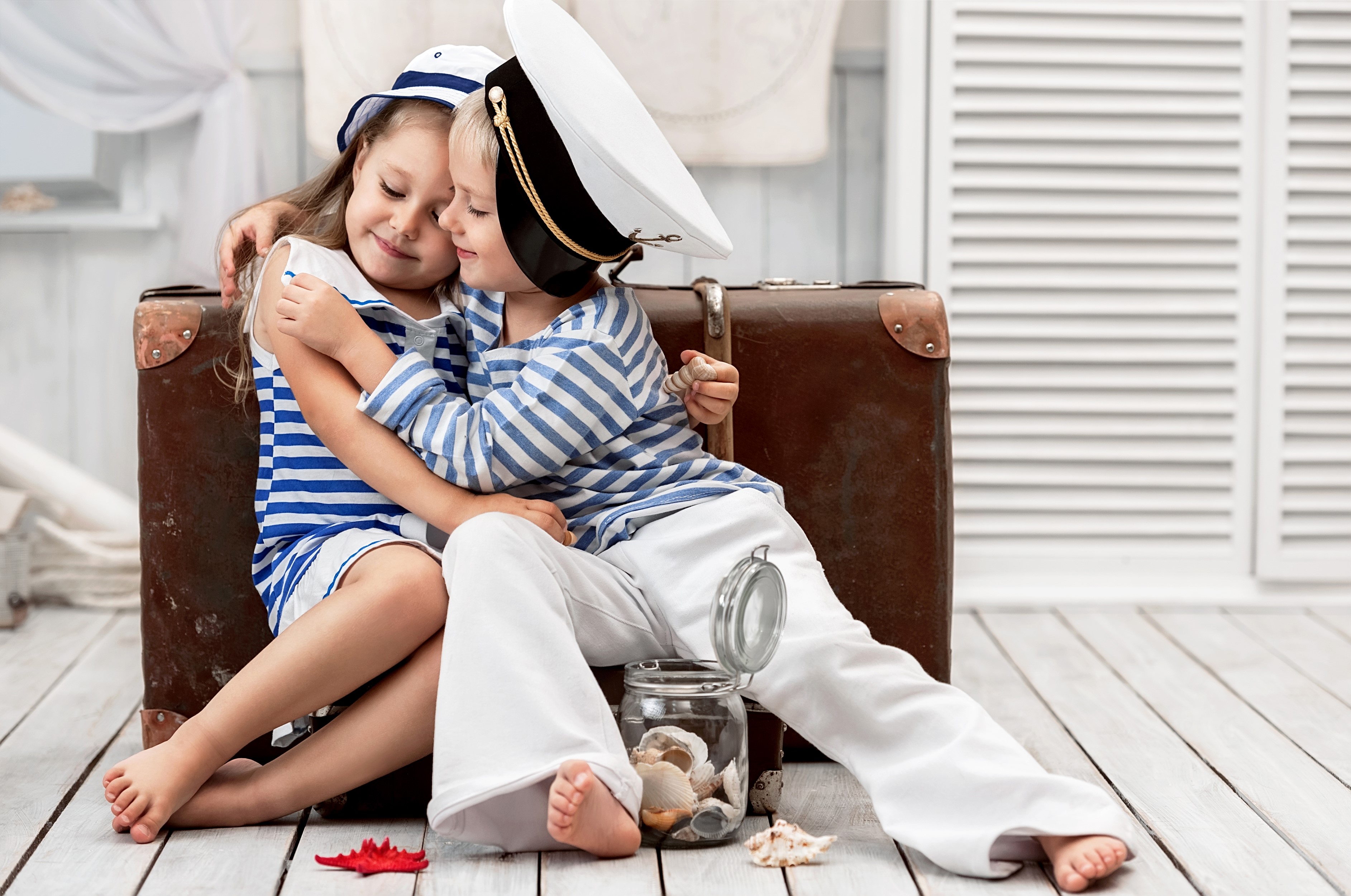 Two children in sailor outfits hugging by a suitcase HD Wallpaper