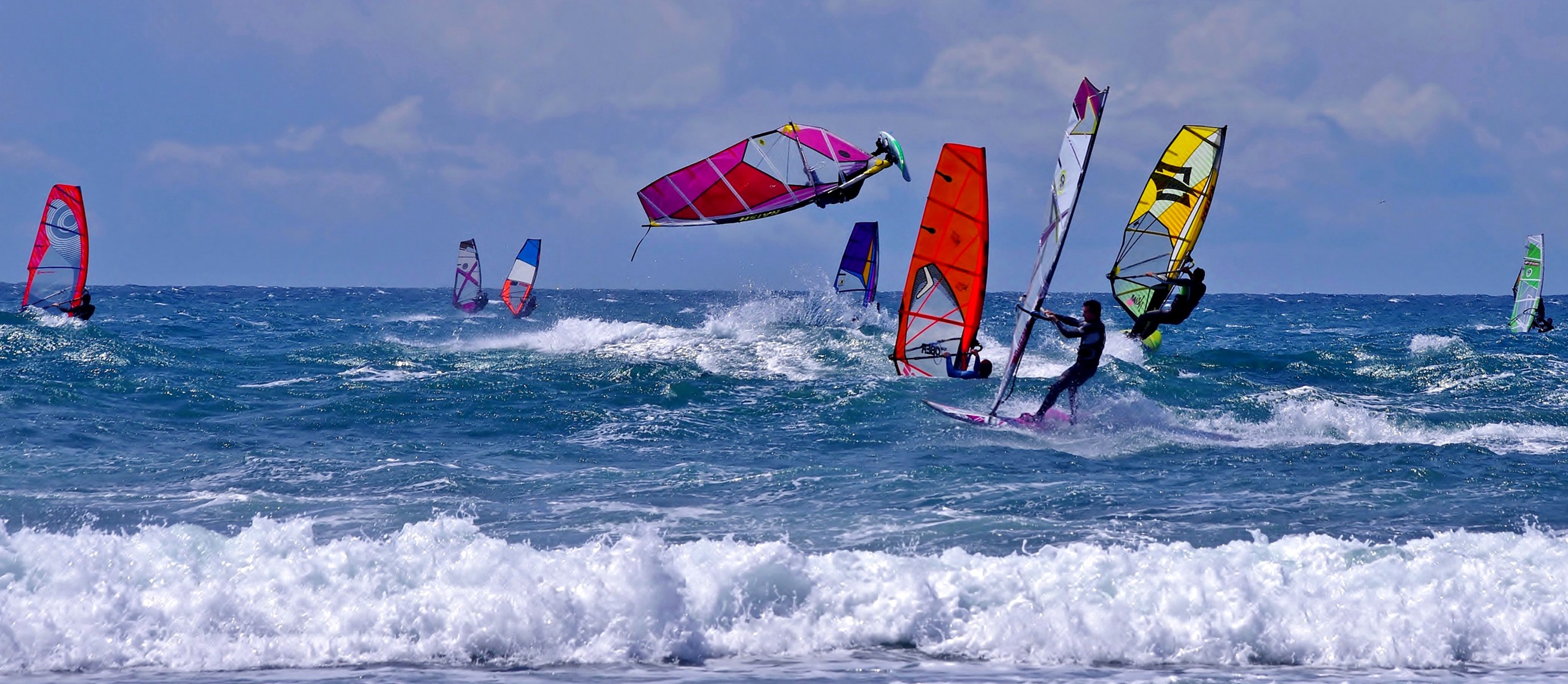 Windsurfers riding waves on a sunny day HD Wallpaper