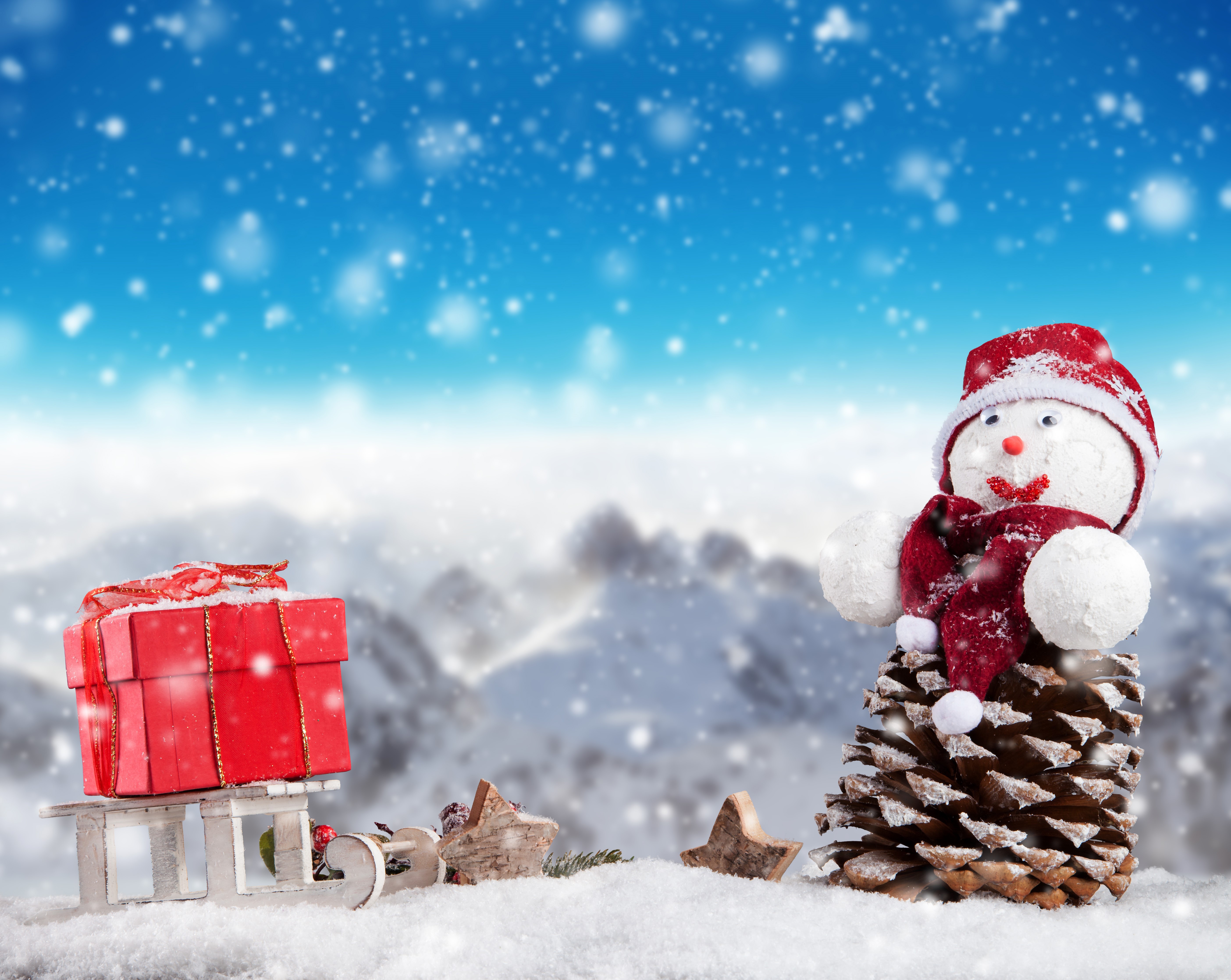Christmas snowman with gift on sled in snowy mountains HD Wallpaper