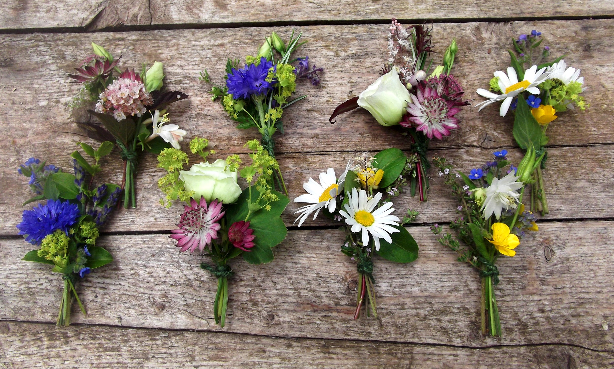 Small floral bouquets with various flowers on a wooden surface HD Wallpaper