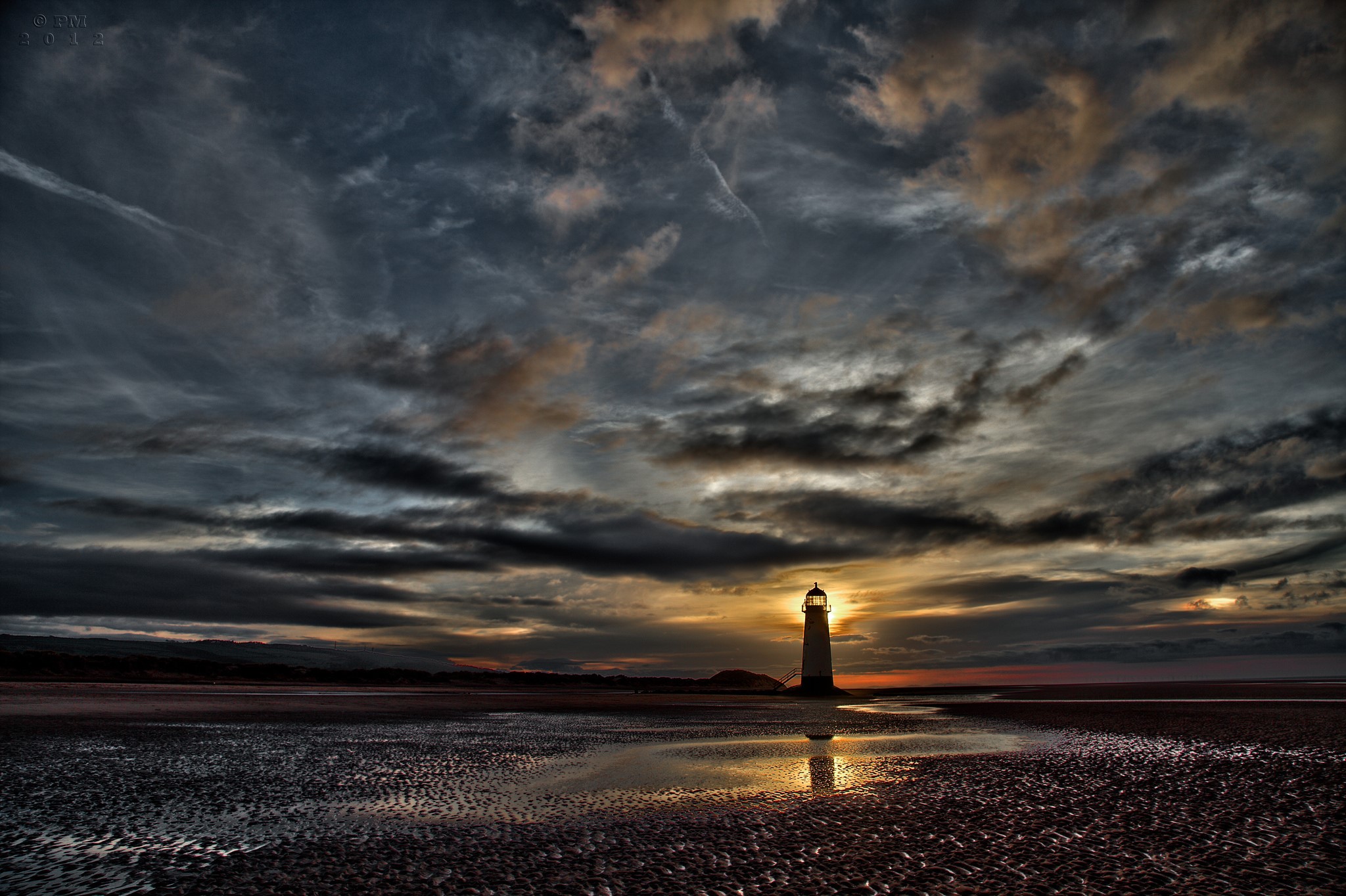 Lighthouse on a beach at sunset with dramatic clouds HD Wallpaper