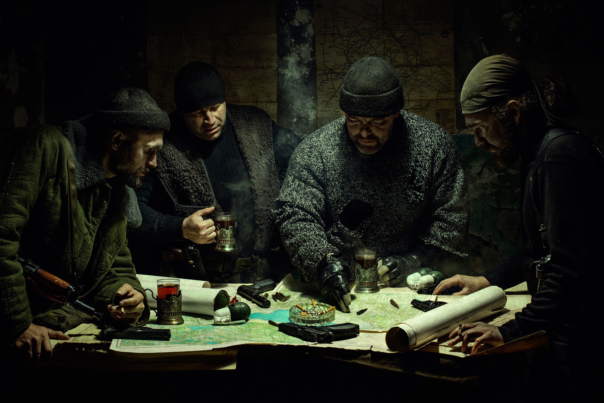 Men gathered around a table with maps and weapons HD Wallpaper