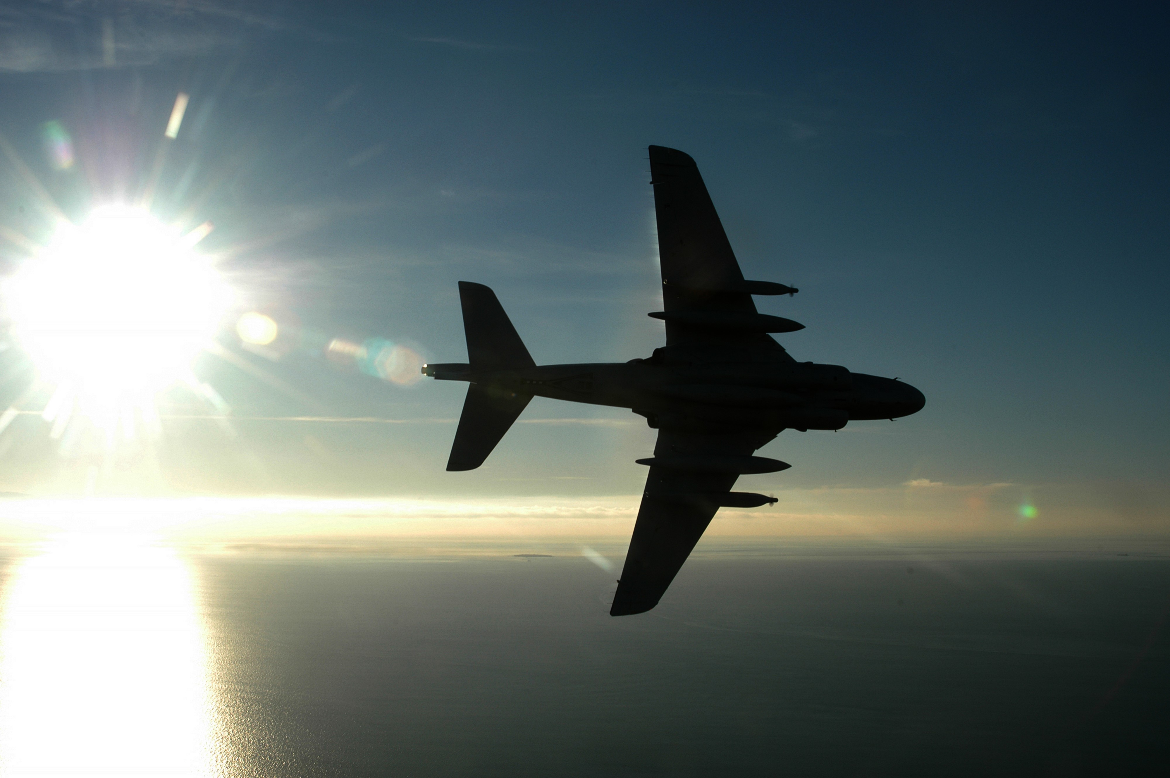 Airplane silhouette against the sun over the ocean HD Wallpaper