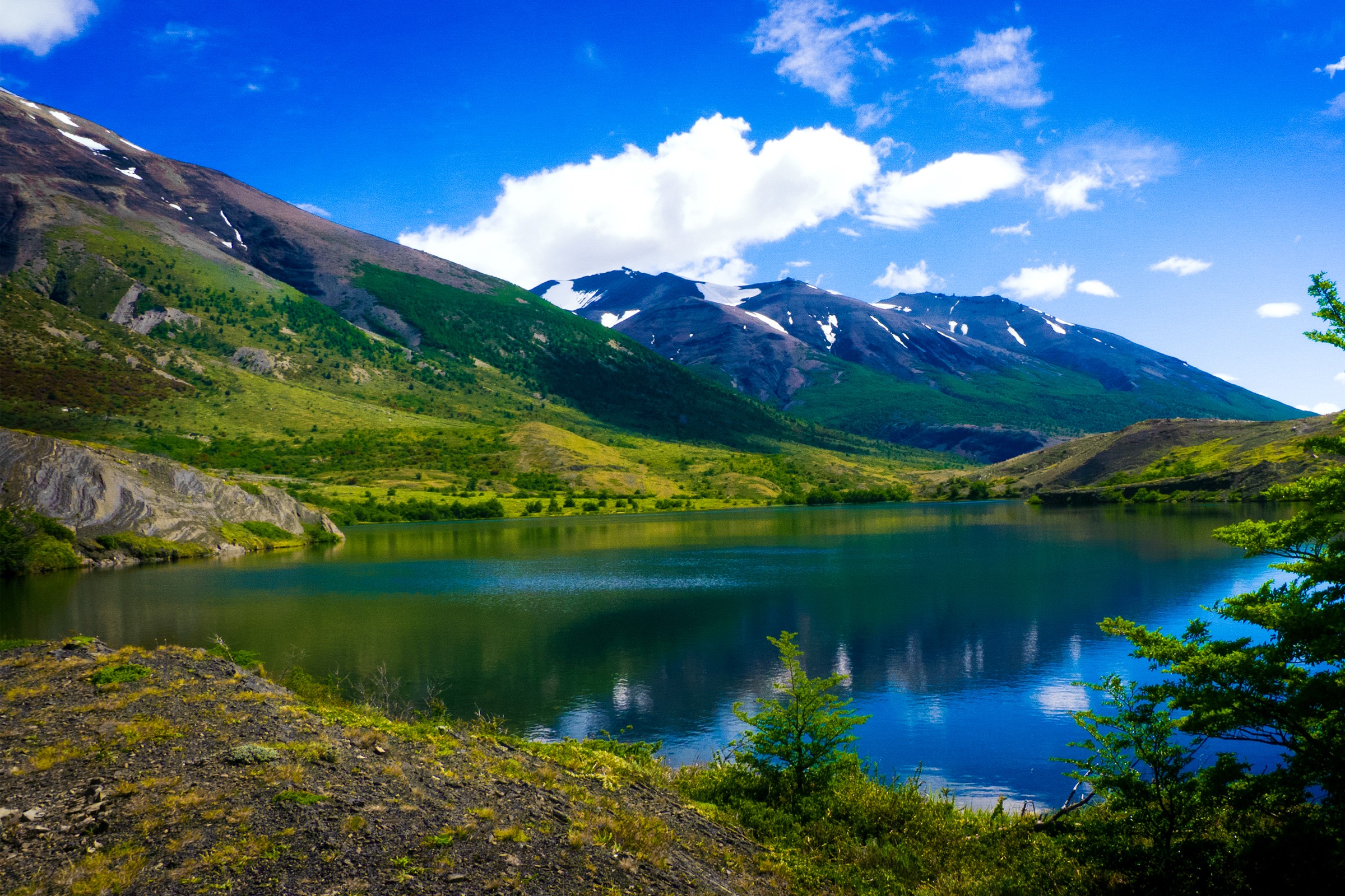 Patagonia, Chile: Mountains reflected in a clear lake under a blue sky HD Wallpaper