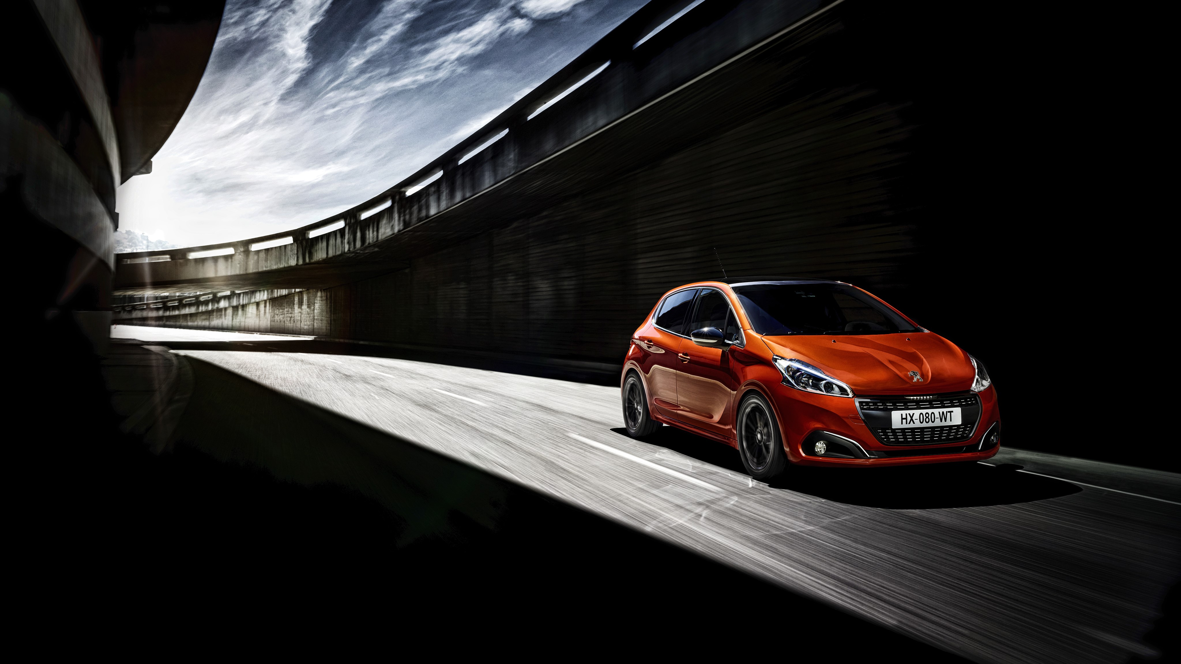 Orange Peugeot 208 driving on a road HD Wallpaper